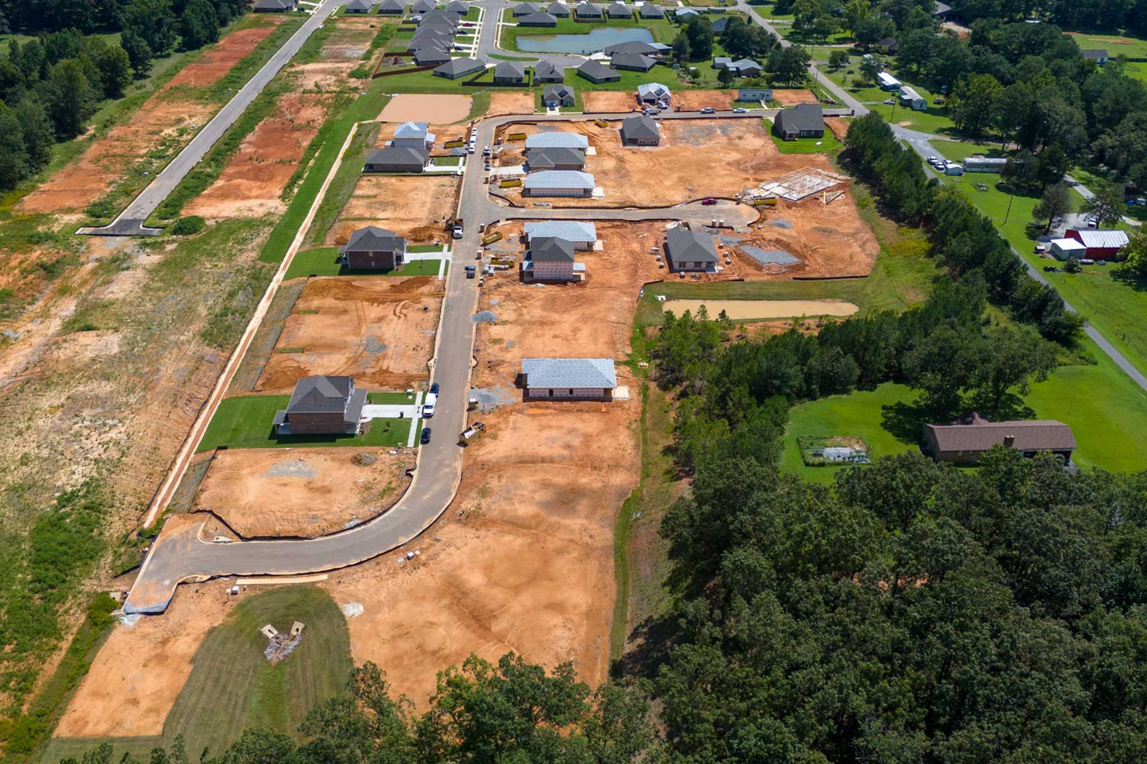 Aerial view of Watts Glen neighborhood in Owens Cross Roads Alabama with new homes under construction amid trees and dirt roads