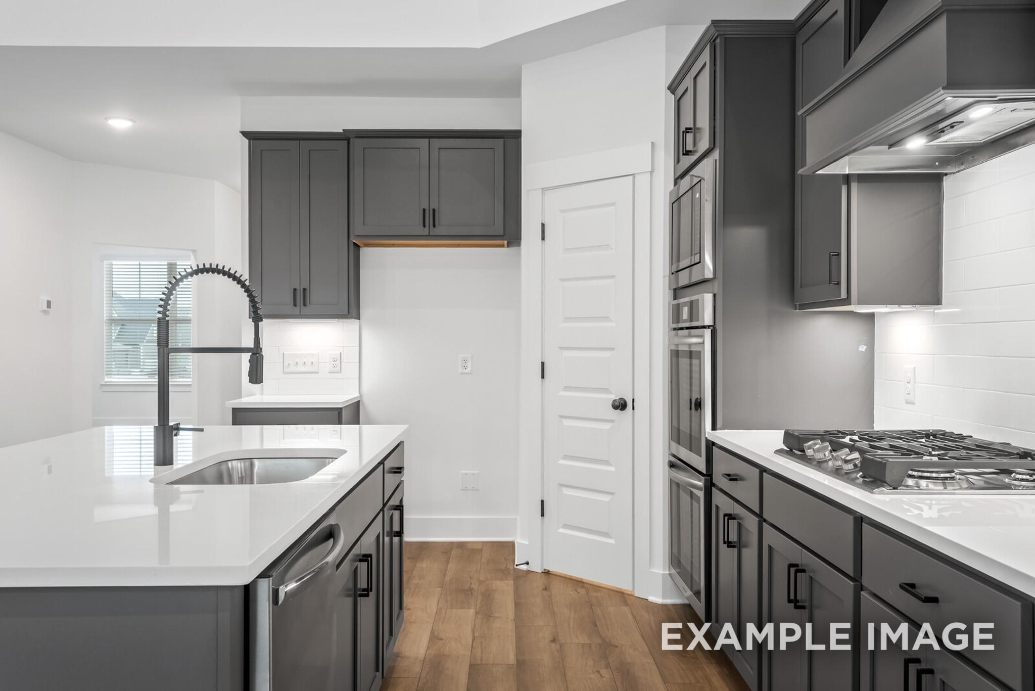 Modern kitchen with gray cabinets, white quartz island, stainless steel appliances in Davidson Homes Ridgeport C, Gallatin, TN