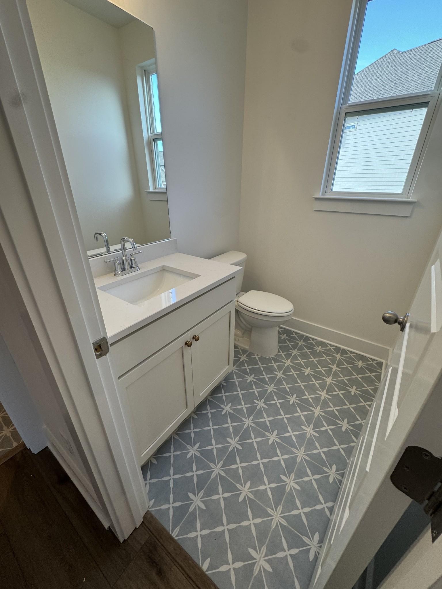 Modern powder room featuring white vanity, single sink, and blue geometric tile floor in Davidson Homes The Ridgeport, Gallatin, TN