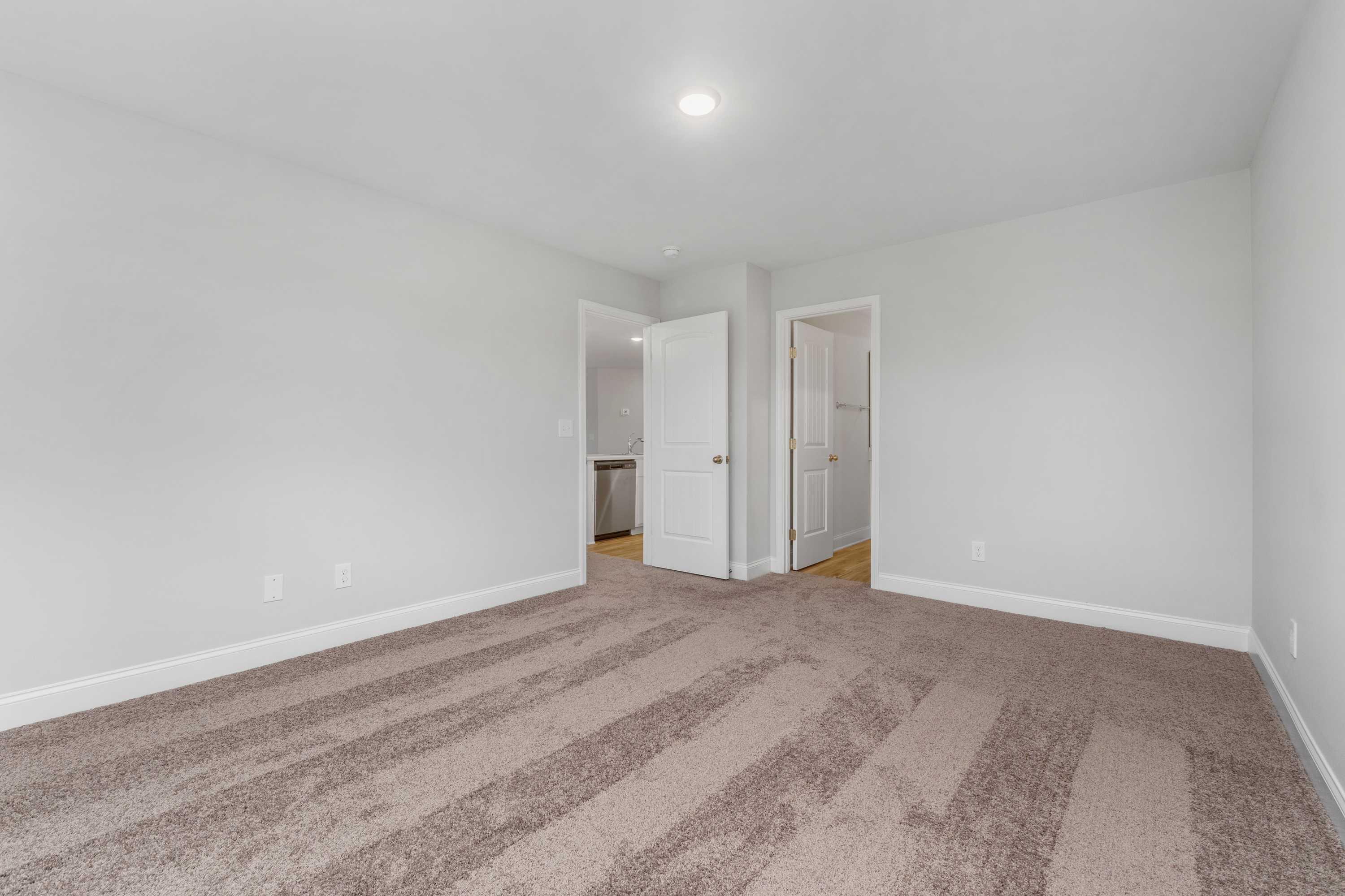 Spacious carpeted bedroom with white walls, bathroom door, and closet in Collins Lane, Meridianville Alabama