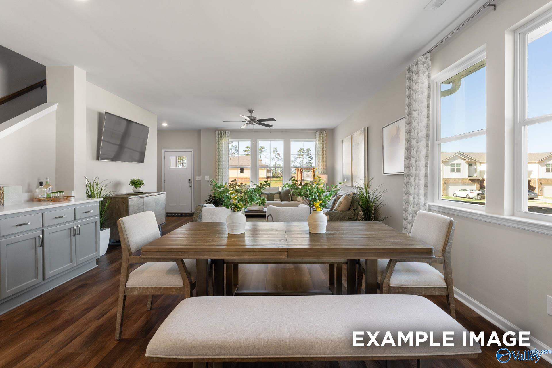 Bright open dining area with wooden table, chairs, plants, and large windows in Davidson Homes The Stella, Madison Alabama