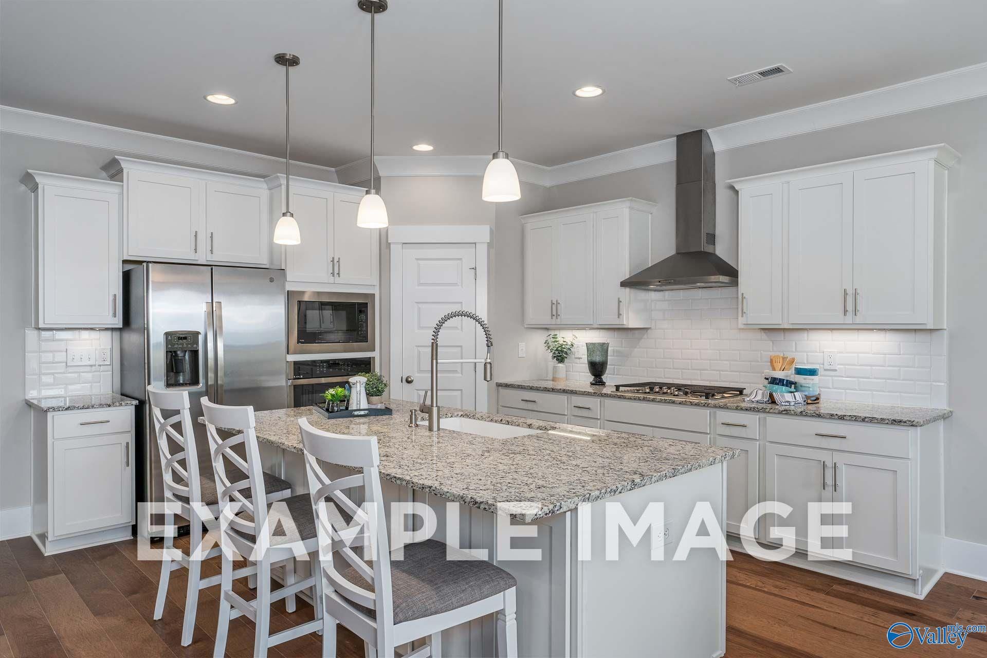 Modern kitchen with white cabinetry, granite island, and stainless appliances in The Harrison floor plan at Cain Park, Hartselle, Alabama