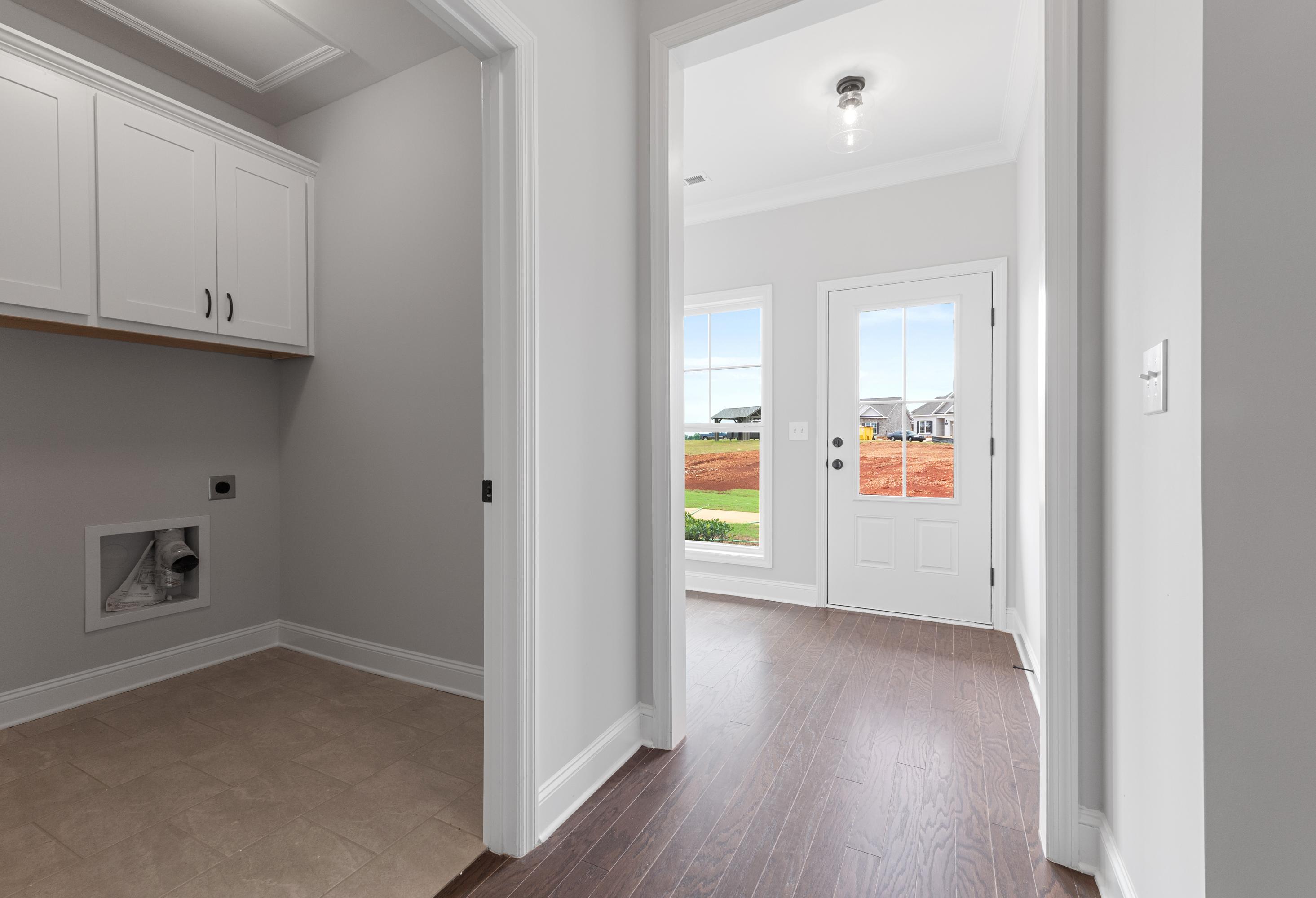 Spacious laundry room in The Copeland with white cabinets, washer dryer hookups, and hallway view to green yard