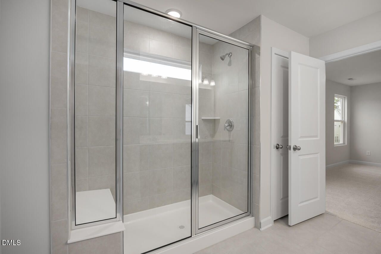 Modern glass walk-in shower with niche shelves in master bath of The Gavin B, Davidson Homes, Lillington, NC