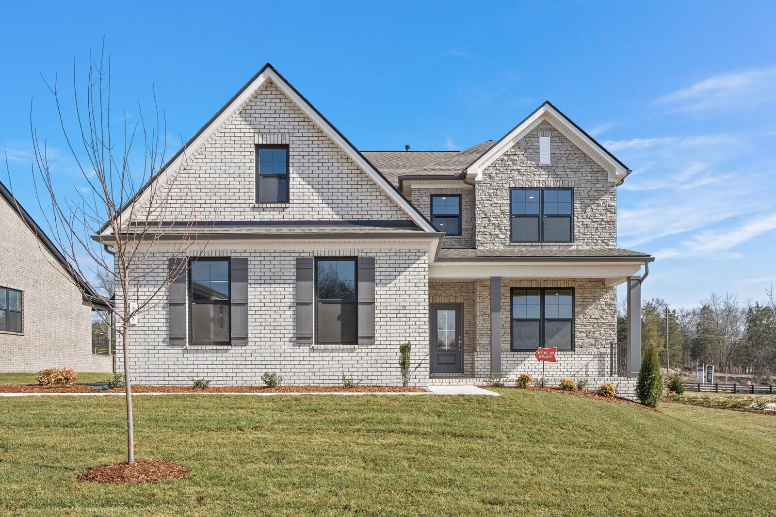 Two-story brick home with gabled roof, covered front porch, and two-car garage on lush green lawn in Benders Cove, Mt. Juliet, Tennessee