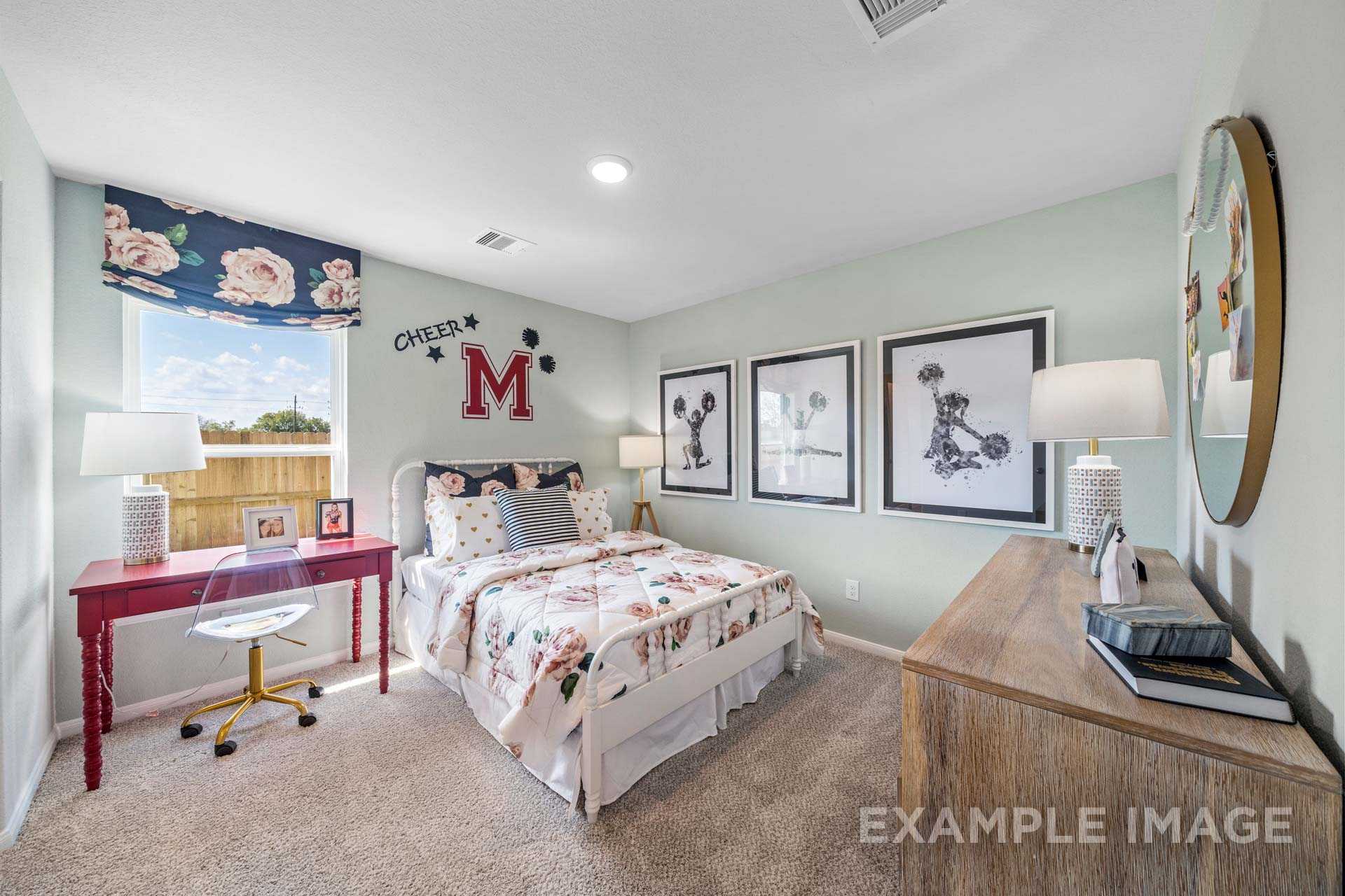 Charming girl's bedroom in The Acadia B with floral bedding, Mickey Mouse art, red desk, and light green walls