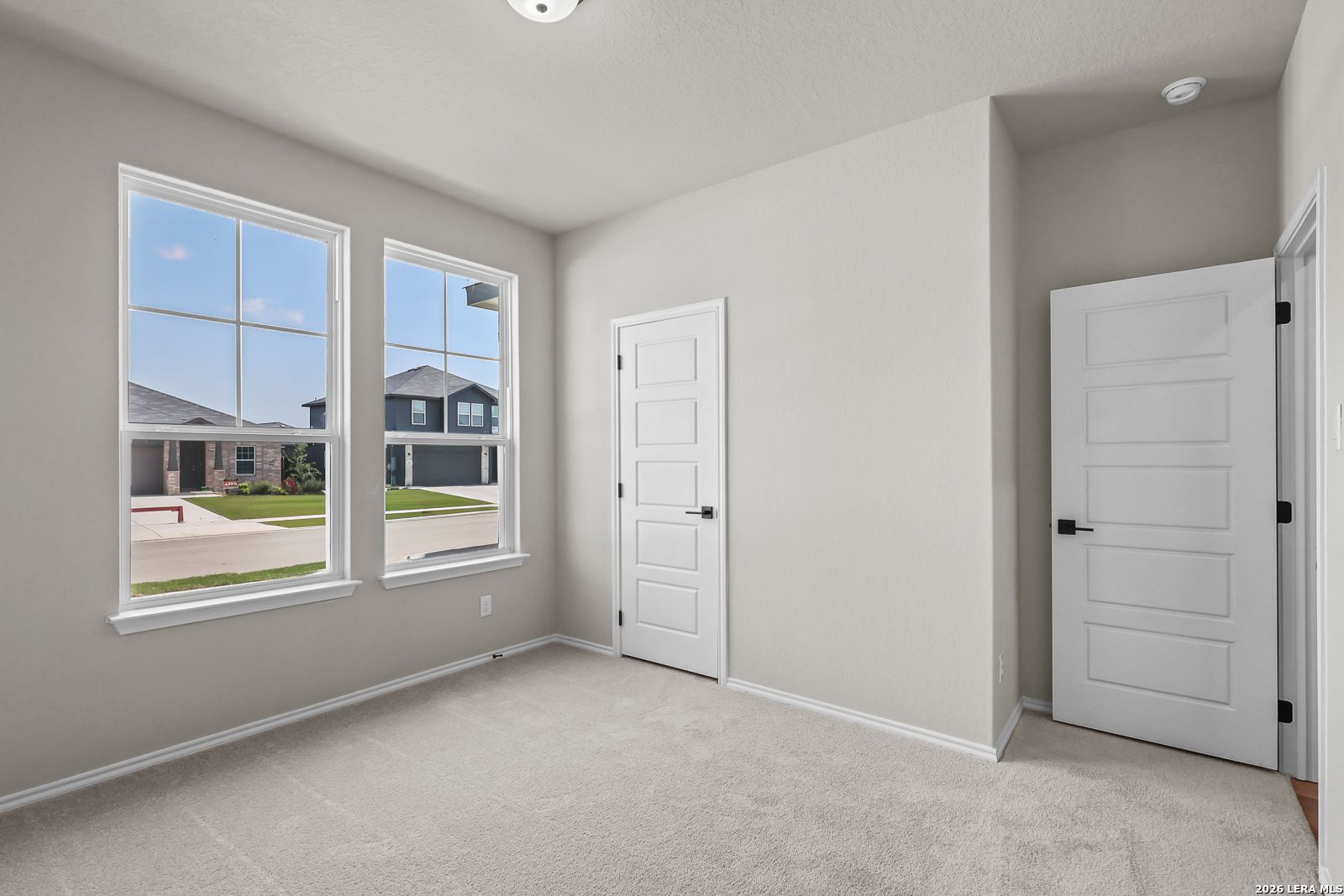 Bright bedroom with neutral carpet and large windows in The Daphne H floor plan at Hannah Heights, Seguin, Texas.