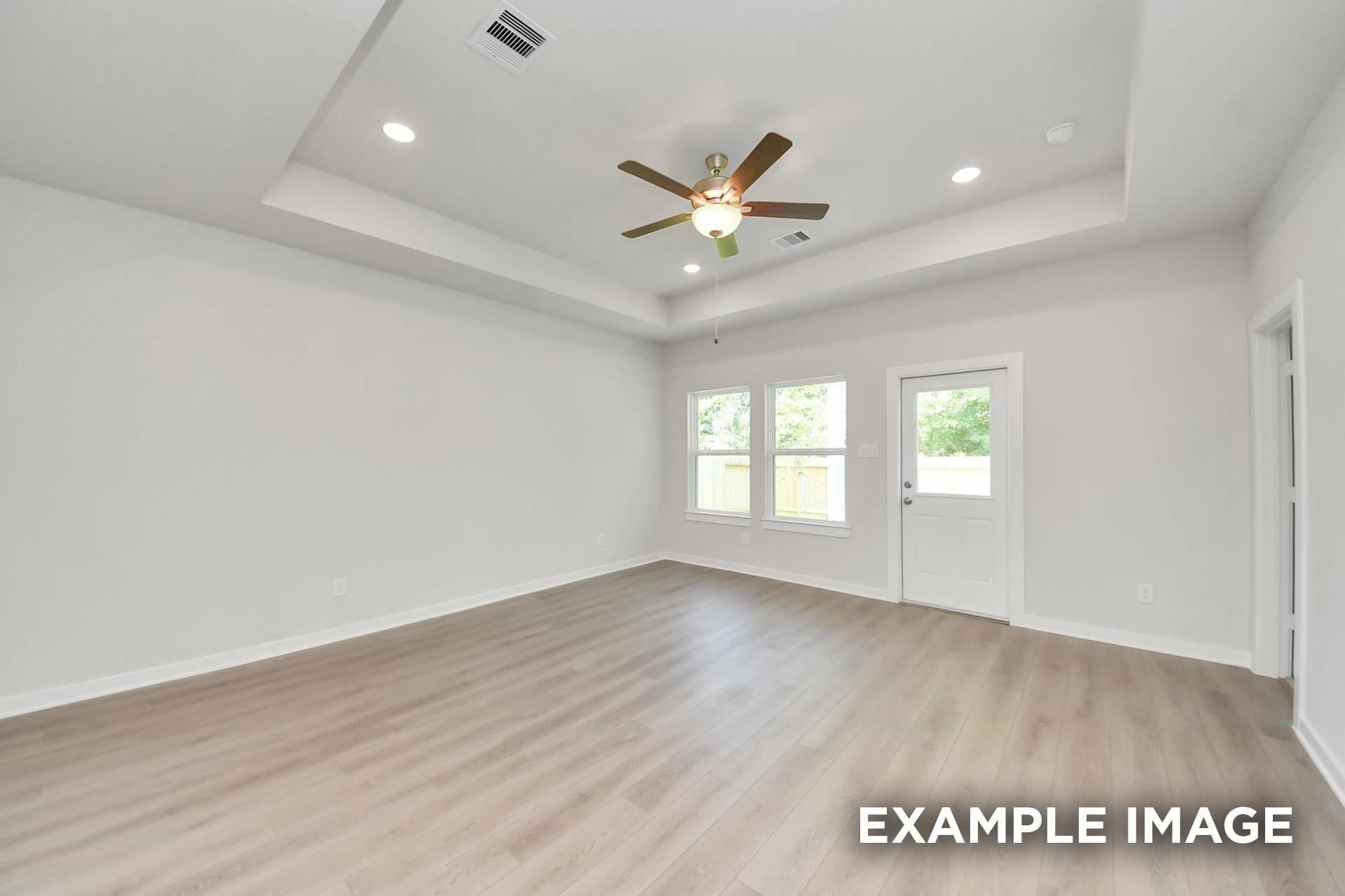 Bright living room with tray ceiling, ceiling fan, and luxury vinyl plank flooring in Davidson Homes The Blanco E, Magnolia, Texas