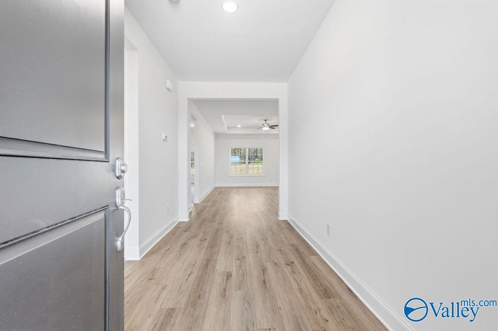 Welcoming entry hallway with open door, white walls, and hardwood floors in Davidson Homes The Montgomery, Hartselle, AL