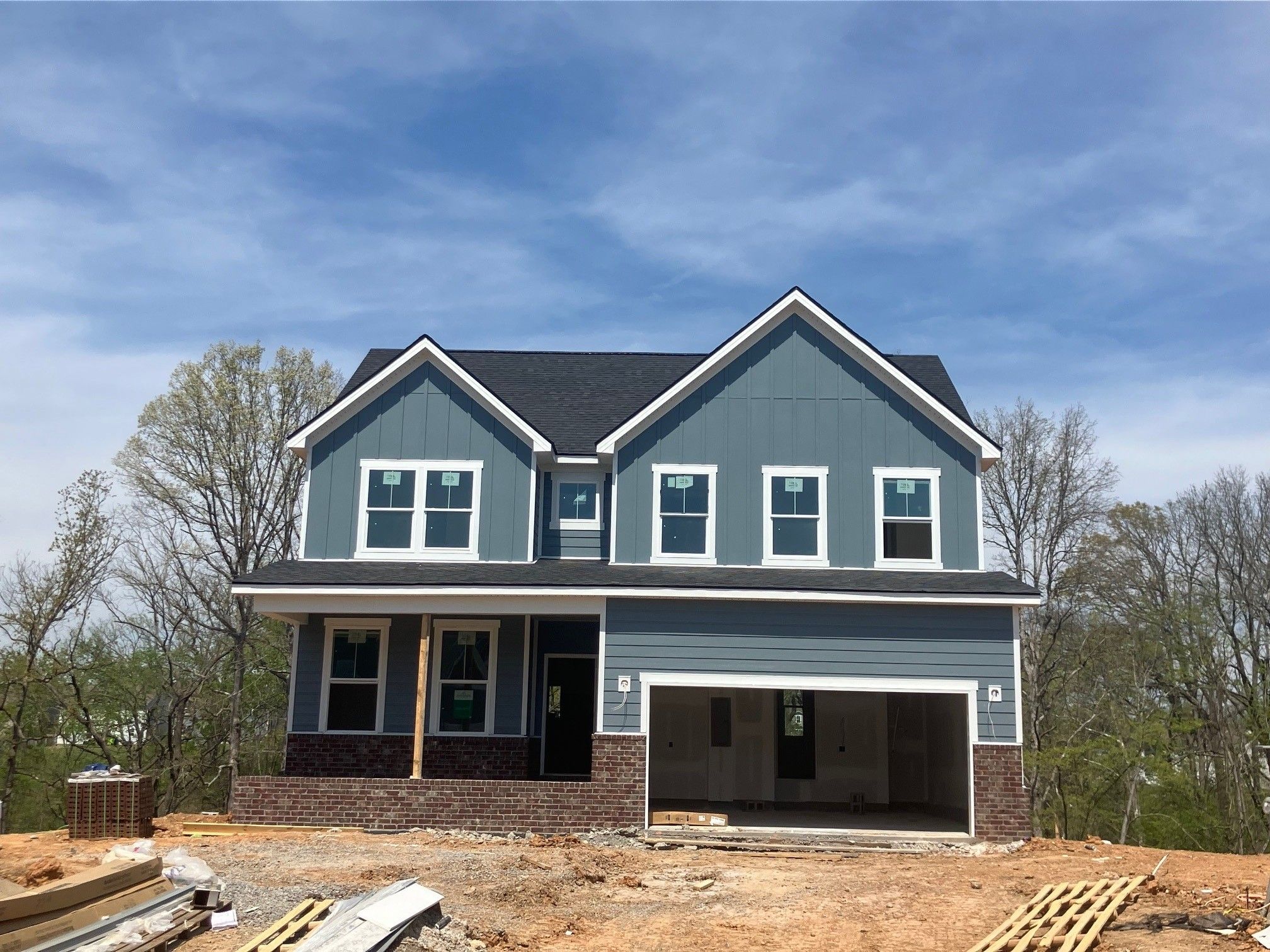 Two-story blue-sided home with open 2-car garage, brick accents, and front porch in Calista Farms, White House, Tennessee