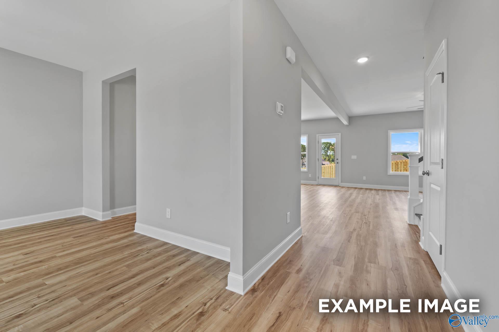 Spacious hallway with light gray walls, oak hardwood floors, and backyard view in Davidson Homes The Shelby B, New Market, Alabama