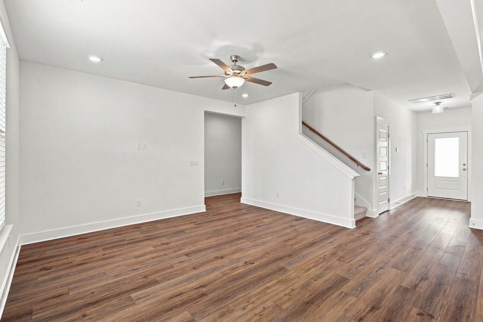 Open living area with wood-look flooring, ceiling fan, and staircase in Davidson Homes The Willow C, Gallatin, Tennessee