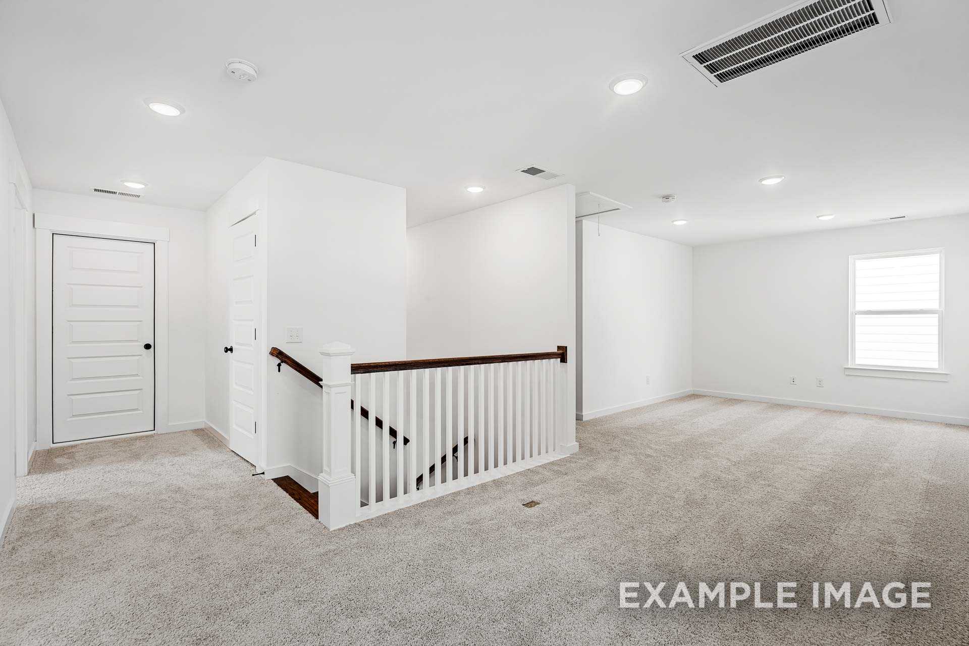 Spacious upstairs landing in The Ash C 2-story home featuring wooden staircase, carpeted floors, white walls, and large windows