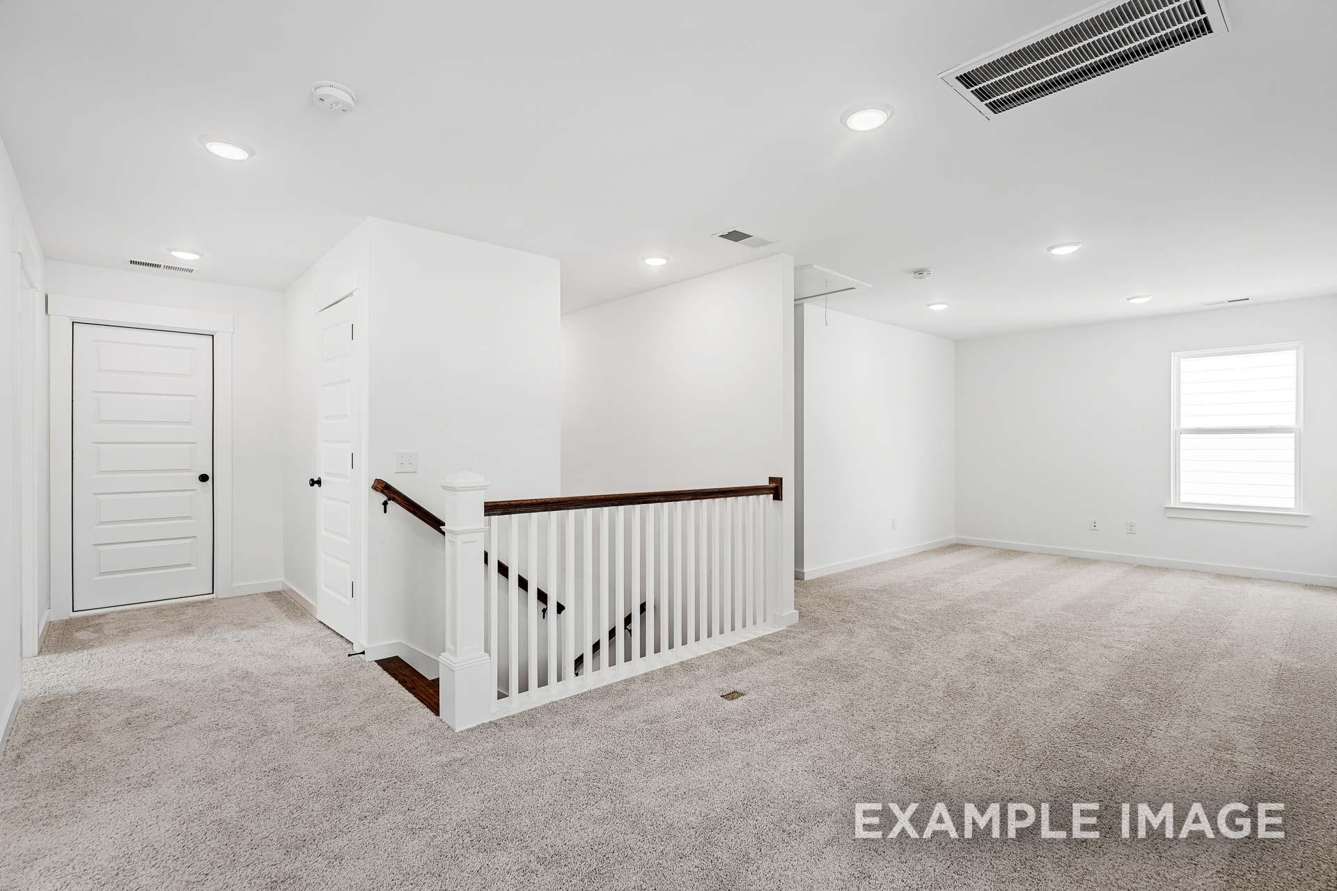 Spacious upstairs landing in The Ash C 2-story home featuring wooden staircase, carpeted floors, white walls, and large windows