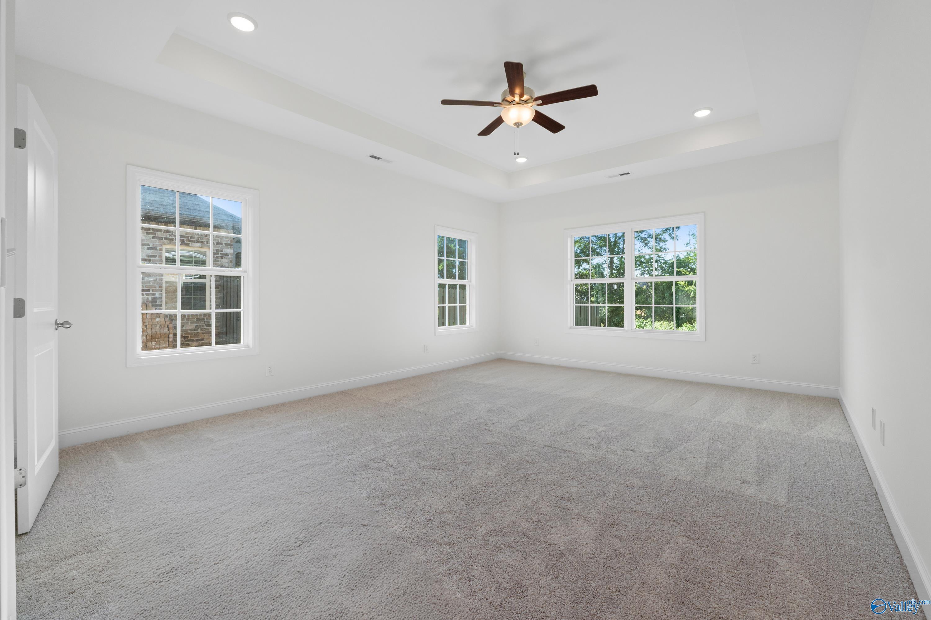 Bright bedroom with large windows, ceiling fan, recessed lights, and plush carpet in Davidson Homes The Oxford, Harvest, Alabama