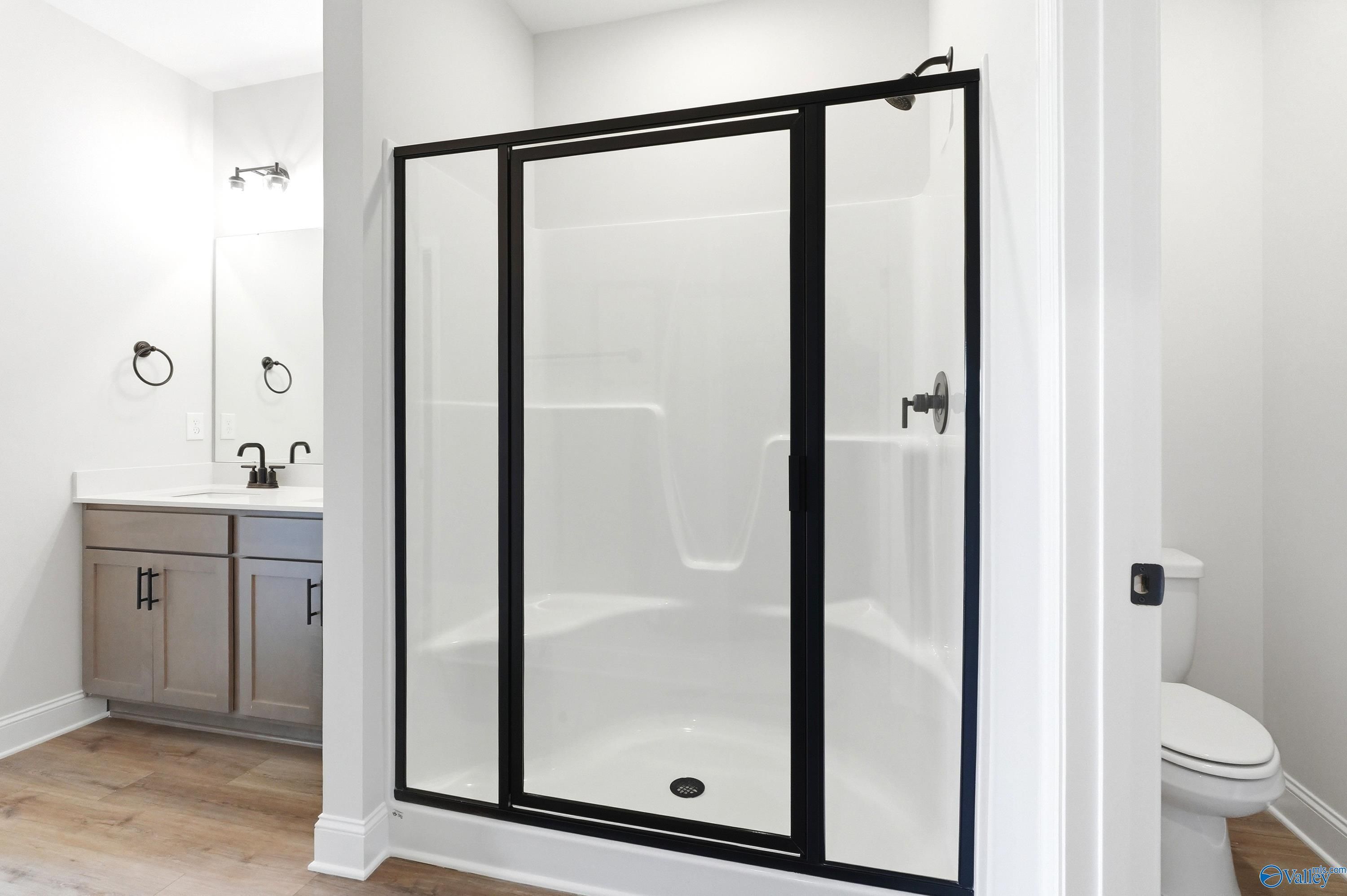 Modern bathroom with walk-in shower, black fixtures, and vanity in The Daphne floor plan at Clearview, Hazel Green, AL.