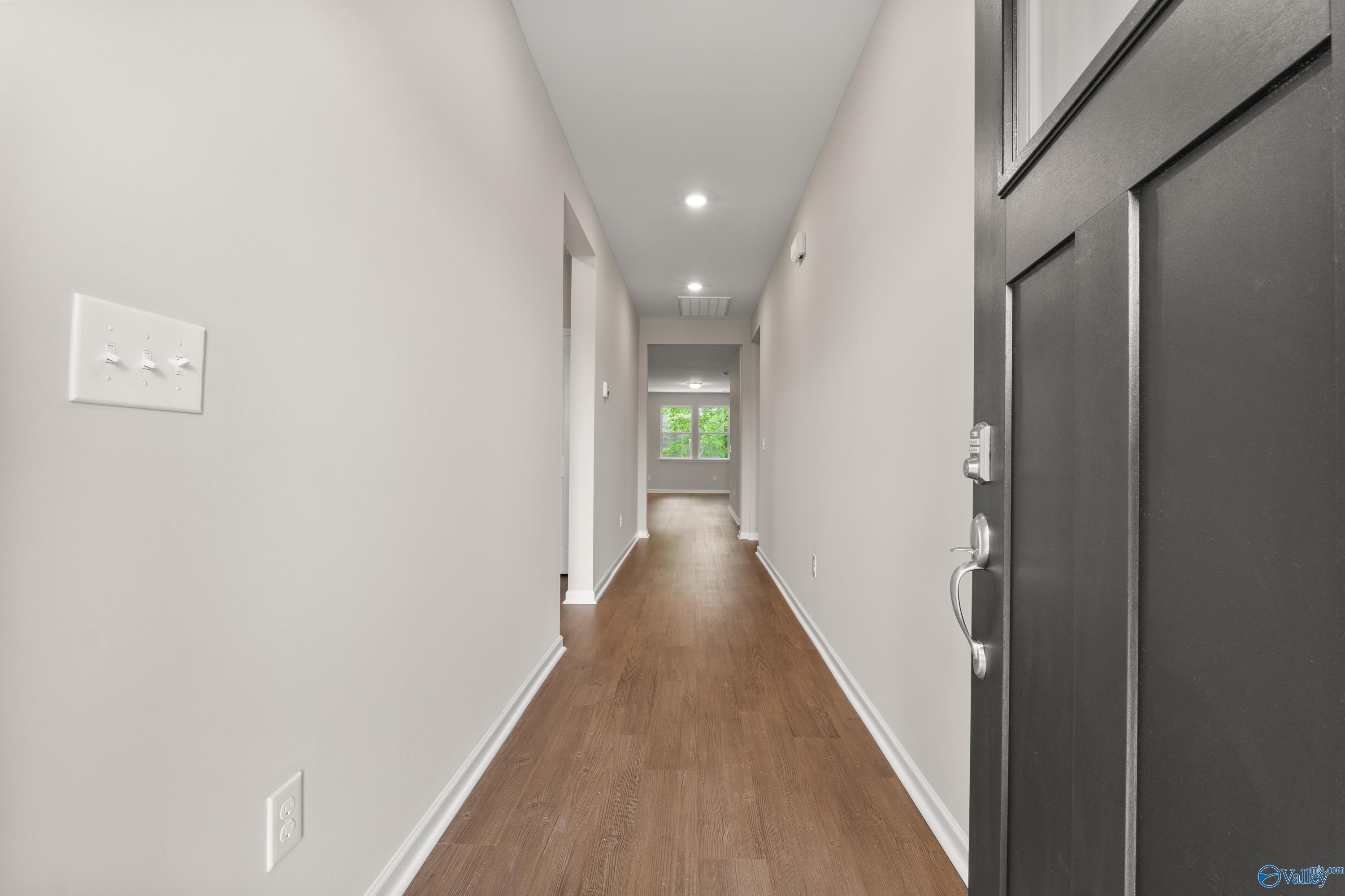 Bright hallway with hardwood floors, light gray walls, and natural light in Davidson Homes The Phoenix, Fayetteville, Tennessee