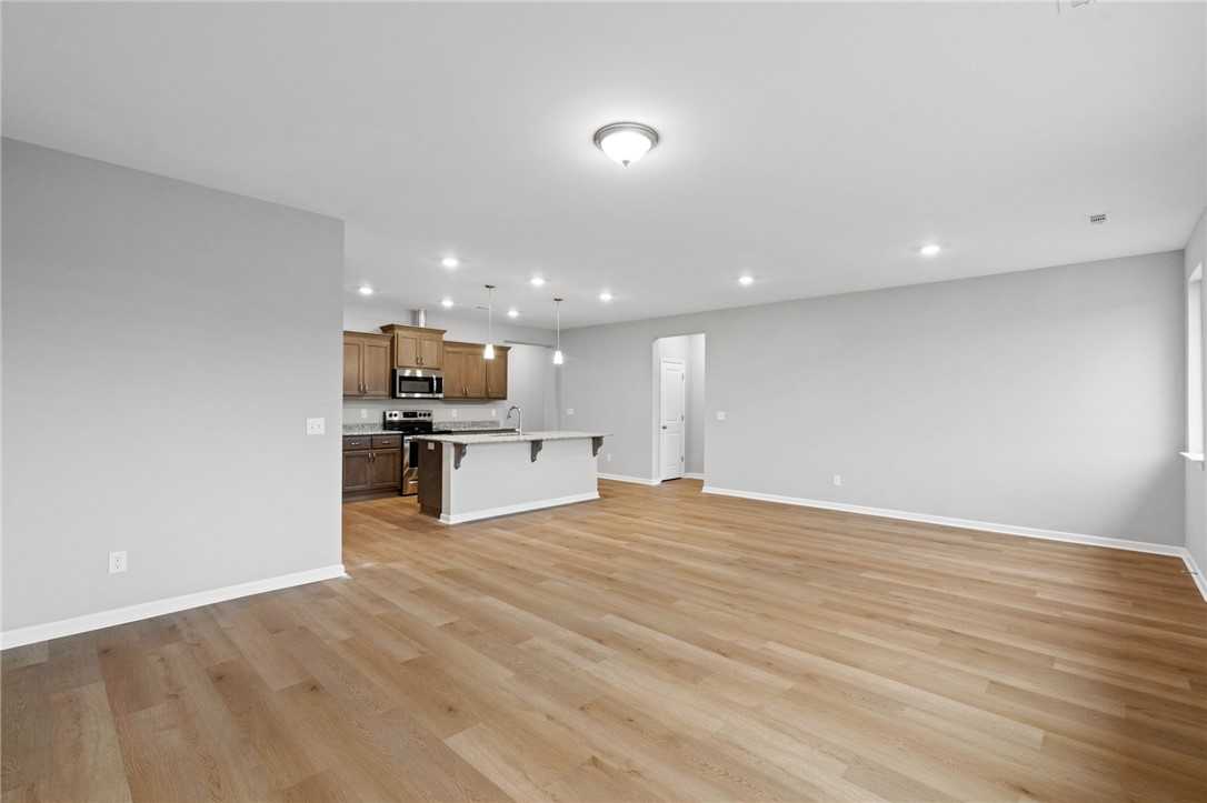 Modern open-concept kitchen with large island, stainless appliances, hardwood floors in The Luna B, Opelika, Alabama