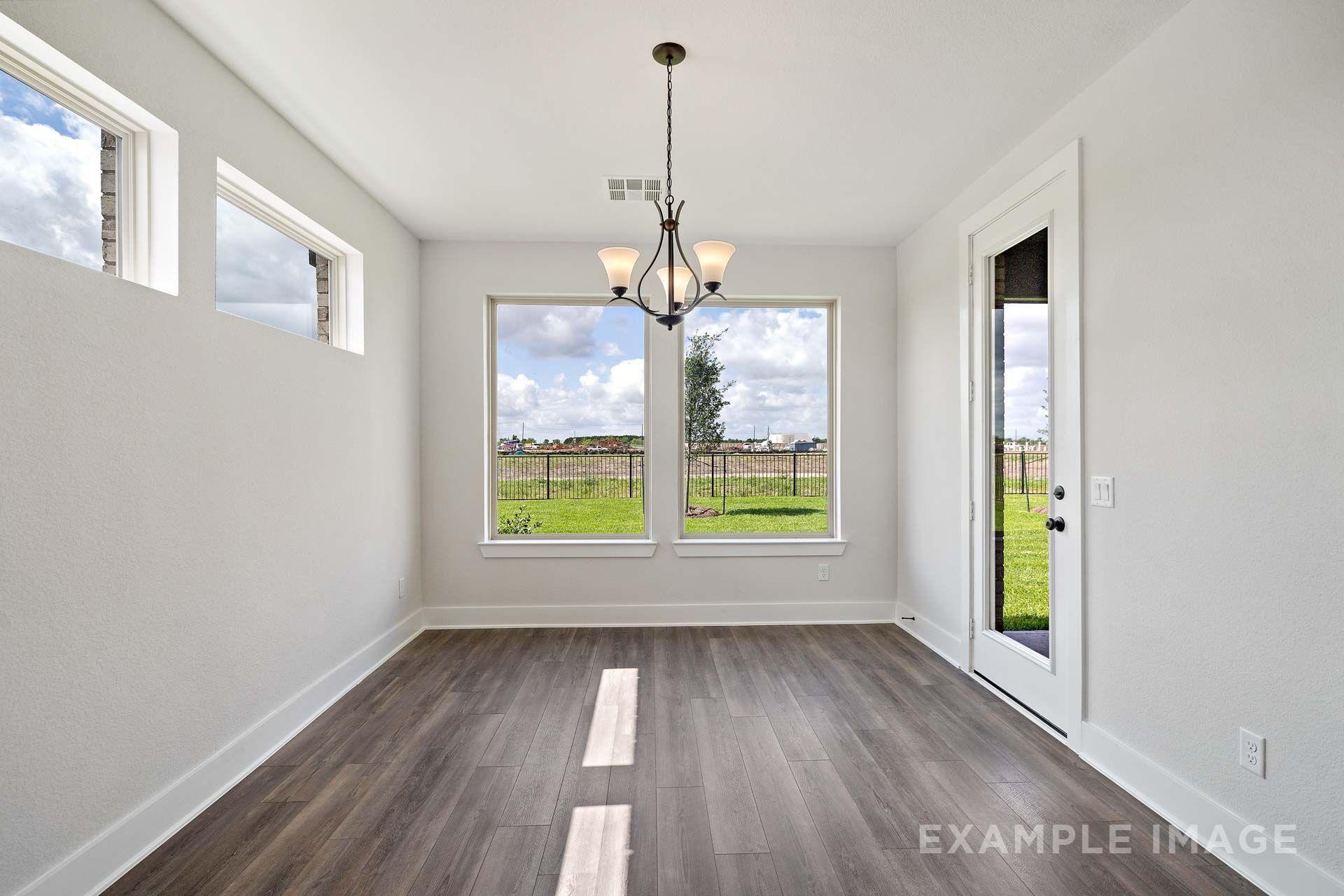 Bright dining room in The Victoria by Davidson Homes with wood-look tile flooring, chandelier, and backyard views.