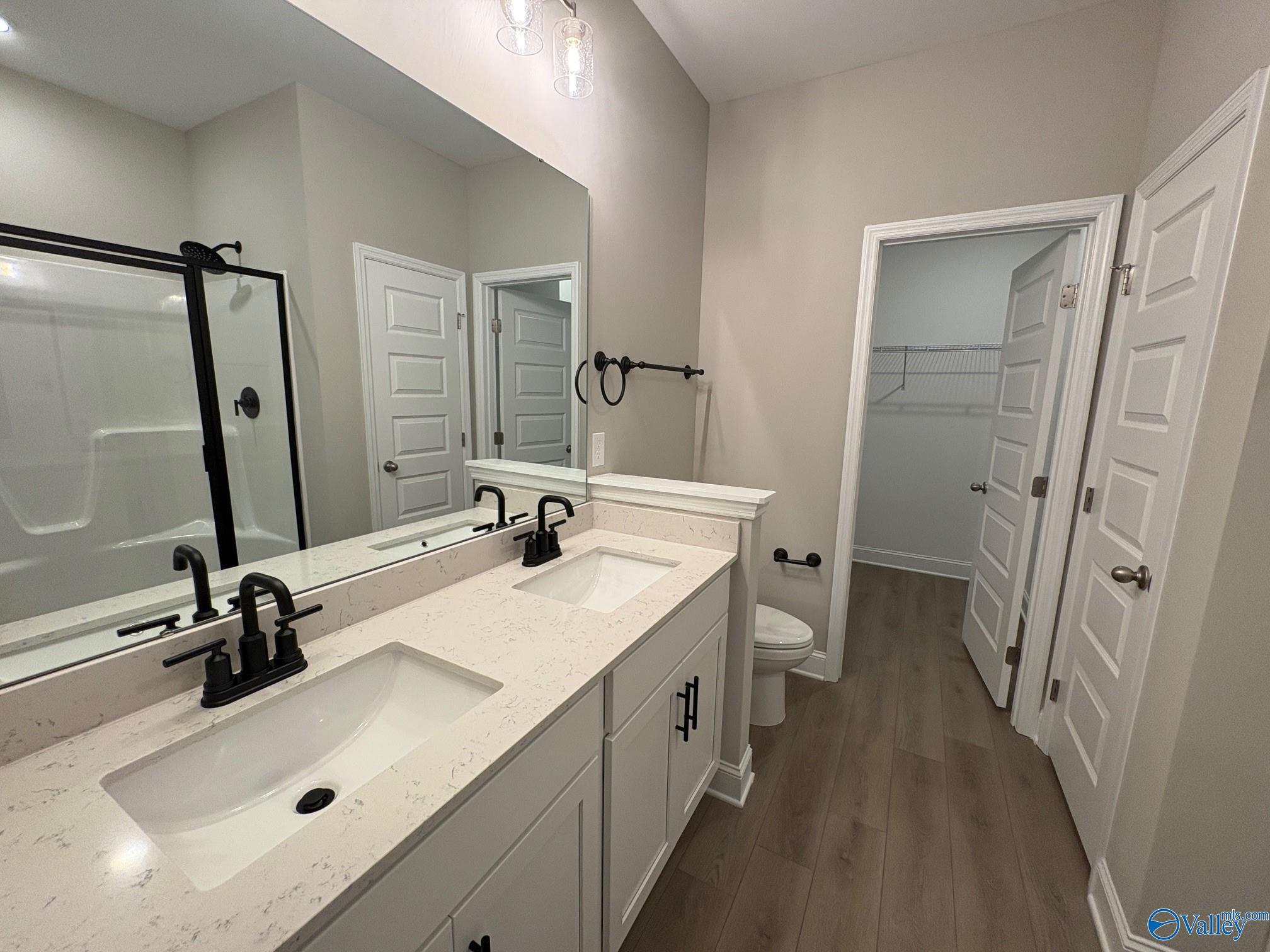 Modern master bathroom featuring double vanity, frameless shower, and walk-in closet in Davidson Homes The Asheville C, Arab, Alabama