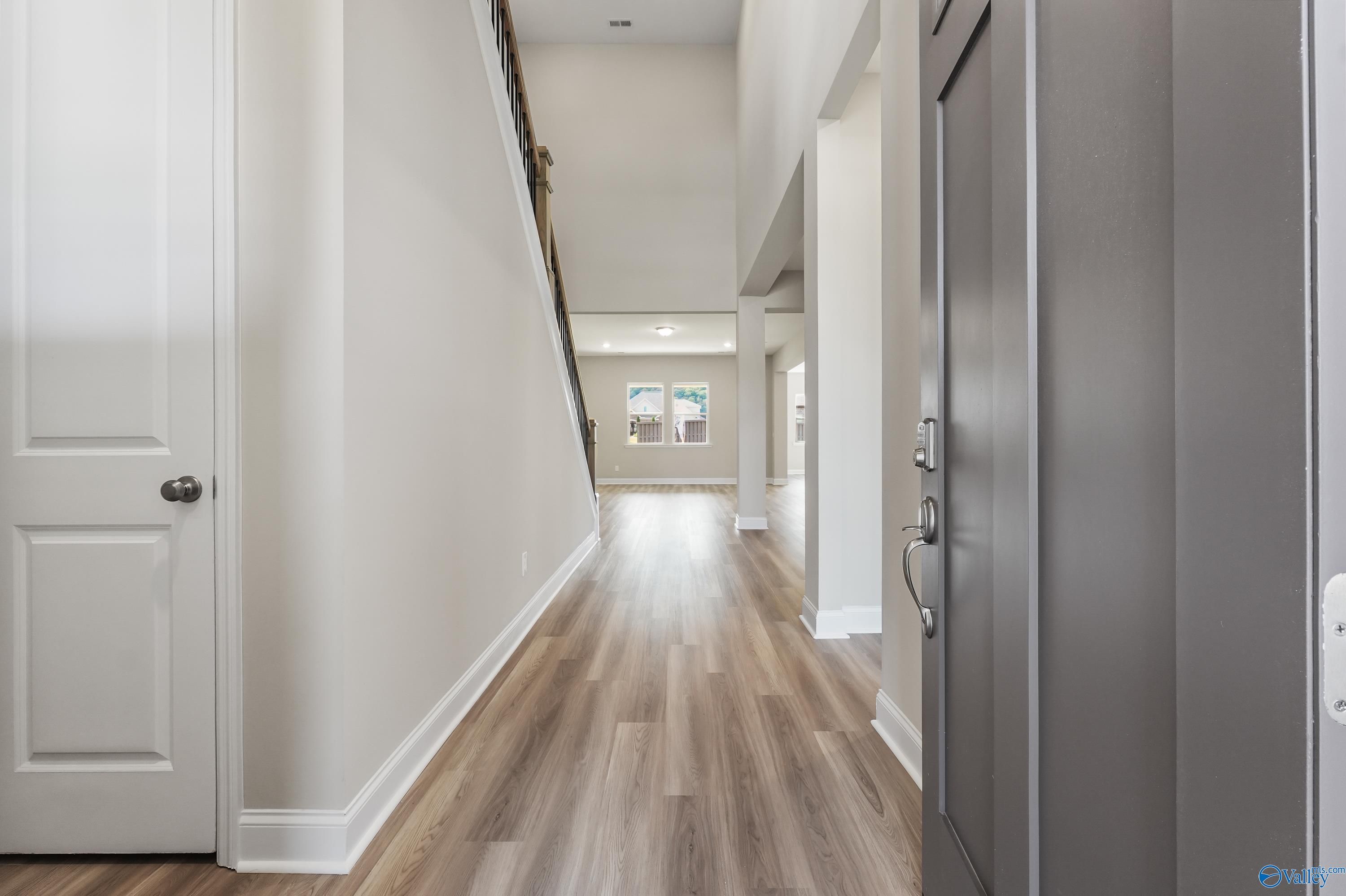 Grand two-story foyer with sweeping staircase, hardwood floors, and neutral walls in Evermore Homes The Haven, Owens Cross Roads, AL