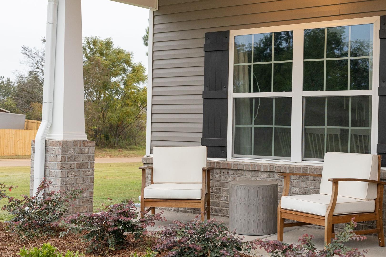Covered front porch with white lounge chairs and gray table at Ivy Glen in Perry, Georgia by Evermore Homes