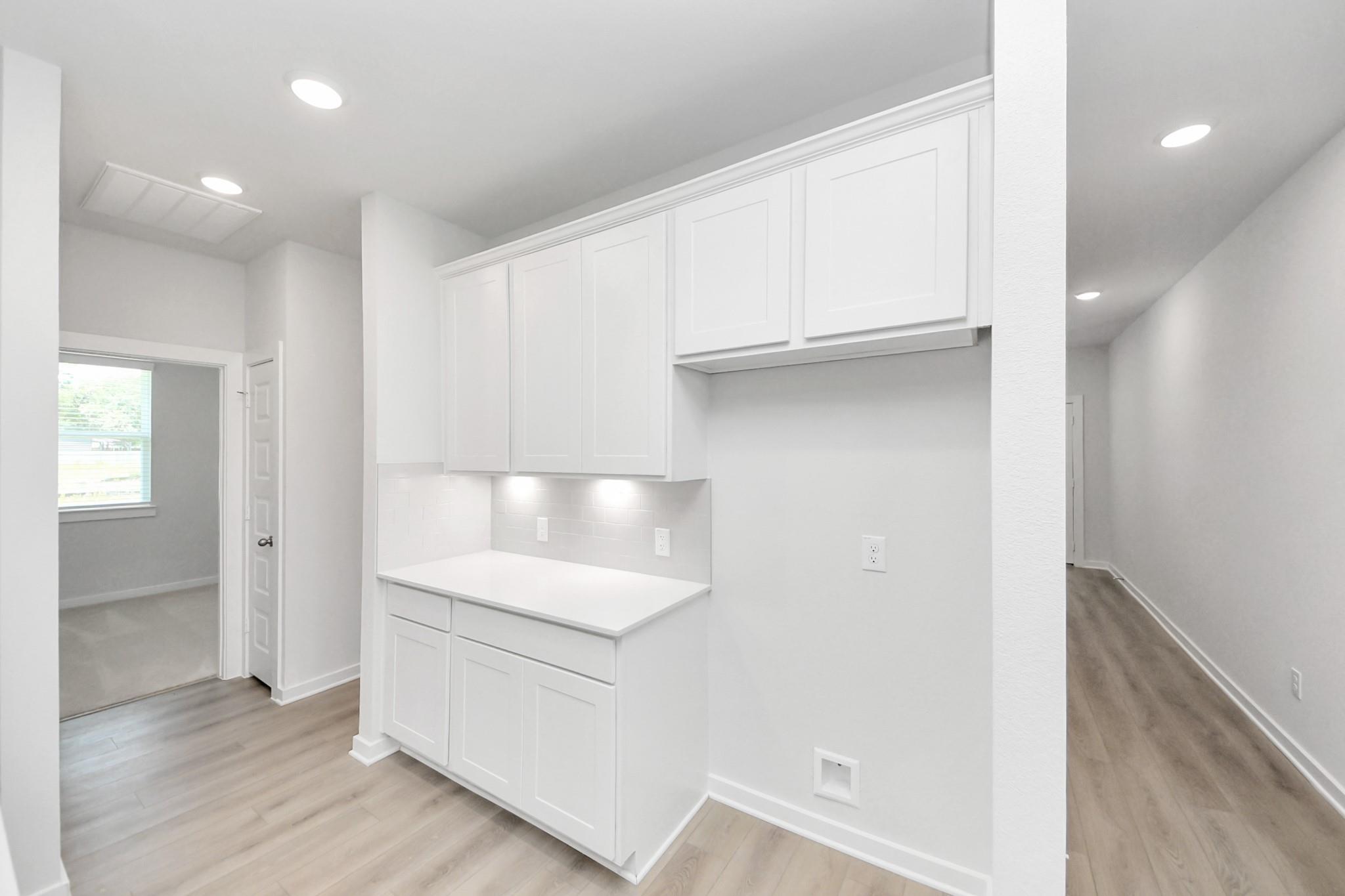 Modern white kitchen butler's pantry with cabinetry and quartz countertops in The Frio F plan, Liberty Estates, Texas.