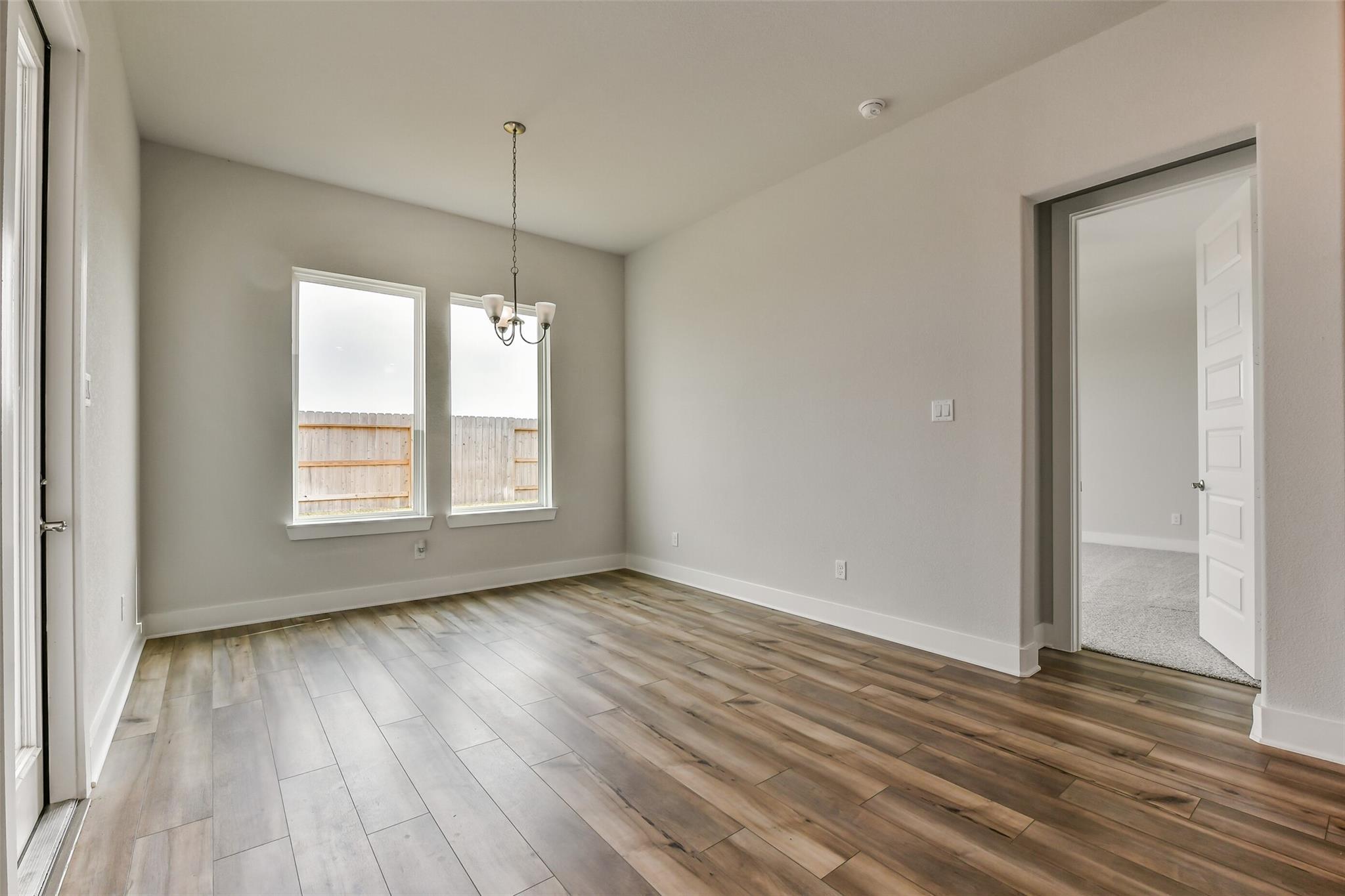 Elegant dining room with chandelier, large windows to backyard, hardwood floors in Davidson Homes The George A, Lago Mar, Texas City