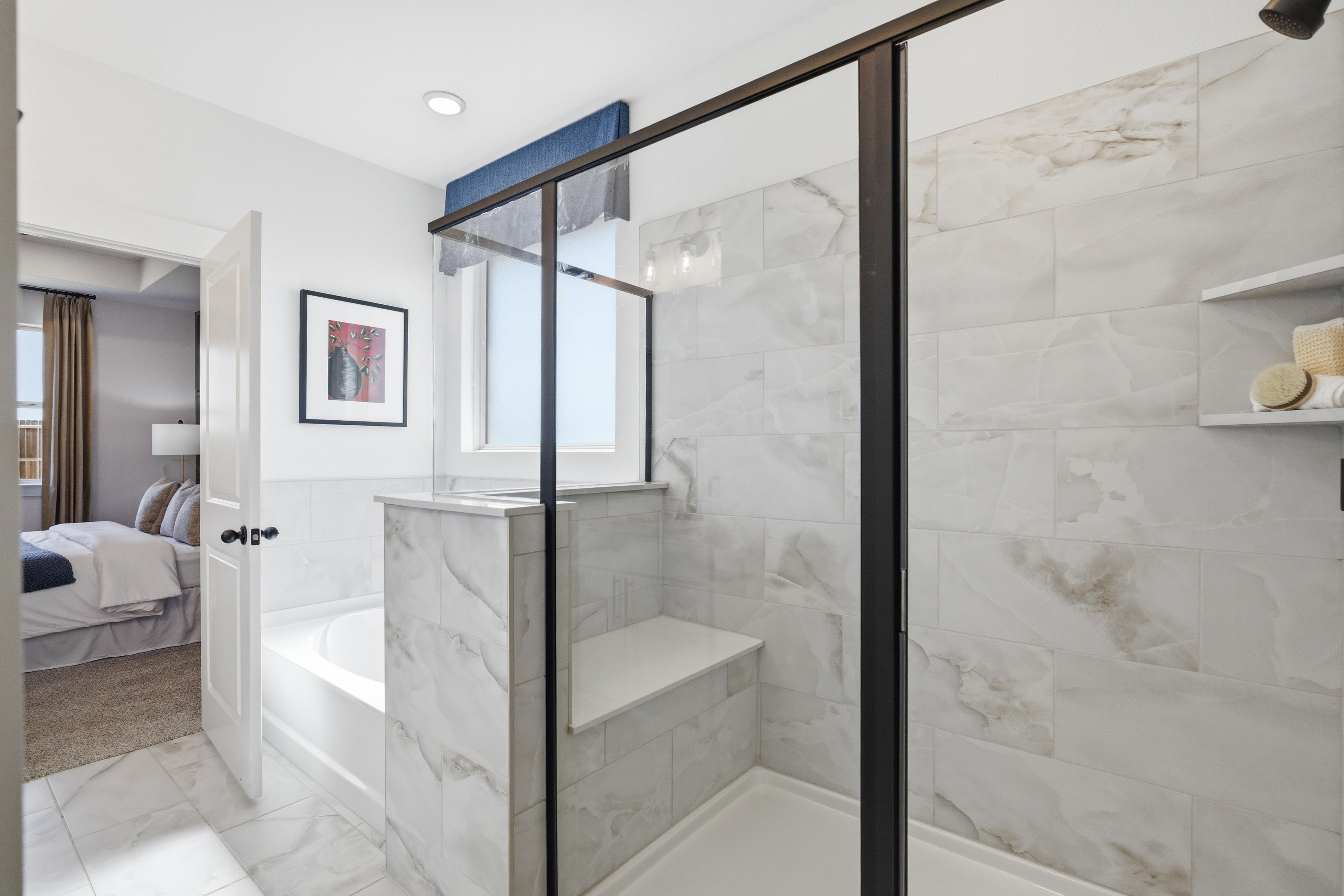 Luxury master bathroom at Mercer Meadows in Royse City TX with white subway tile, glass shower bench, freestanding tub