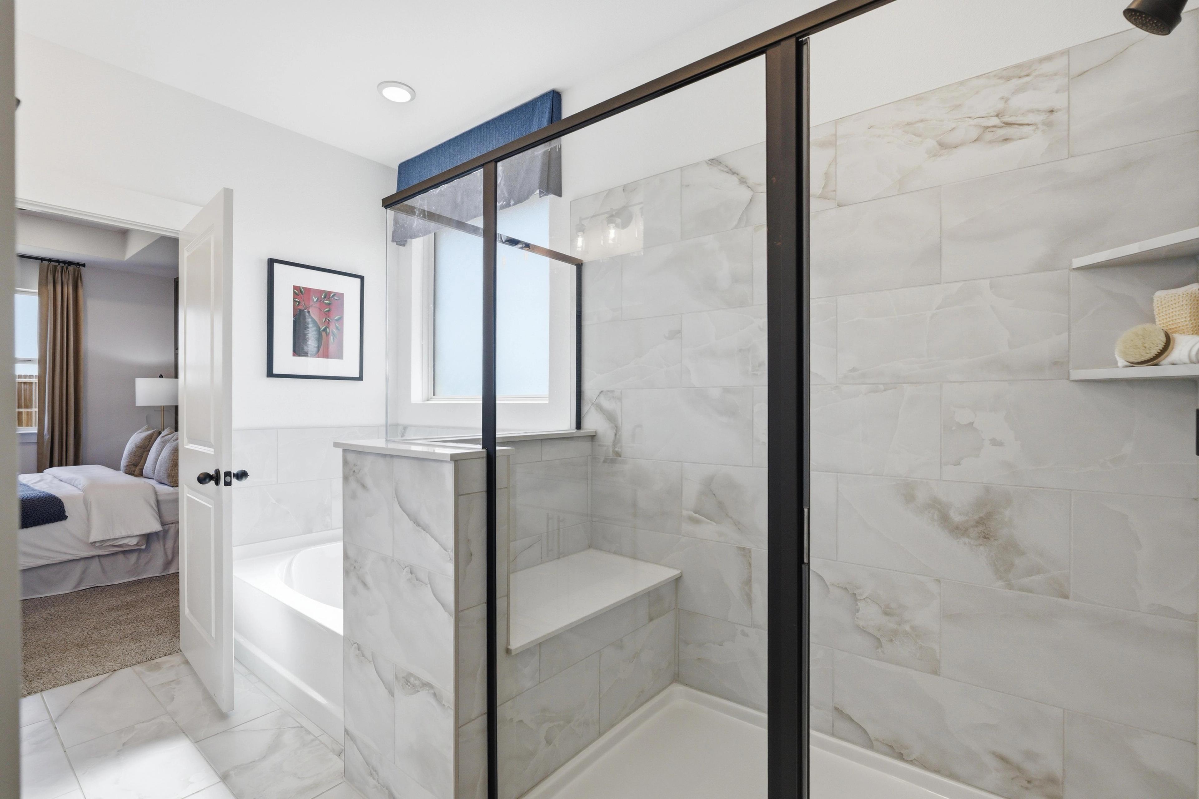 Luxury master bathroom at Mercer Meadows in Royse City TX with white subway tile, glass shower bench, freestanding tub