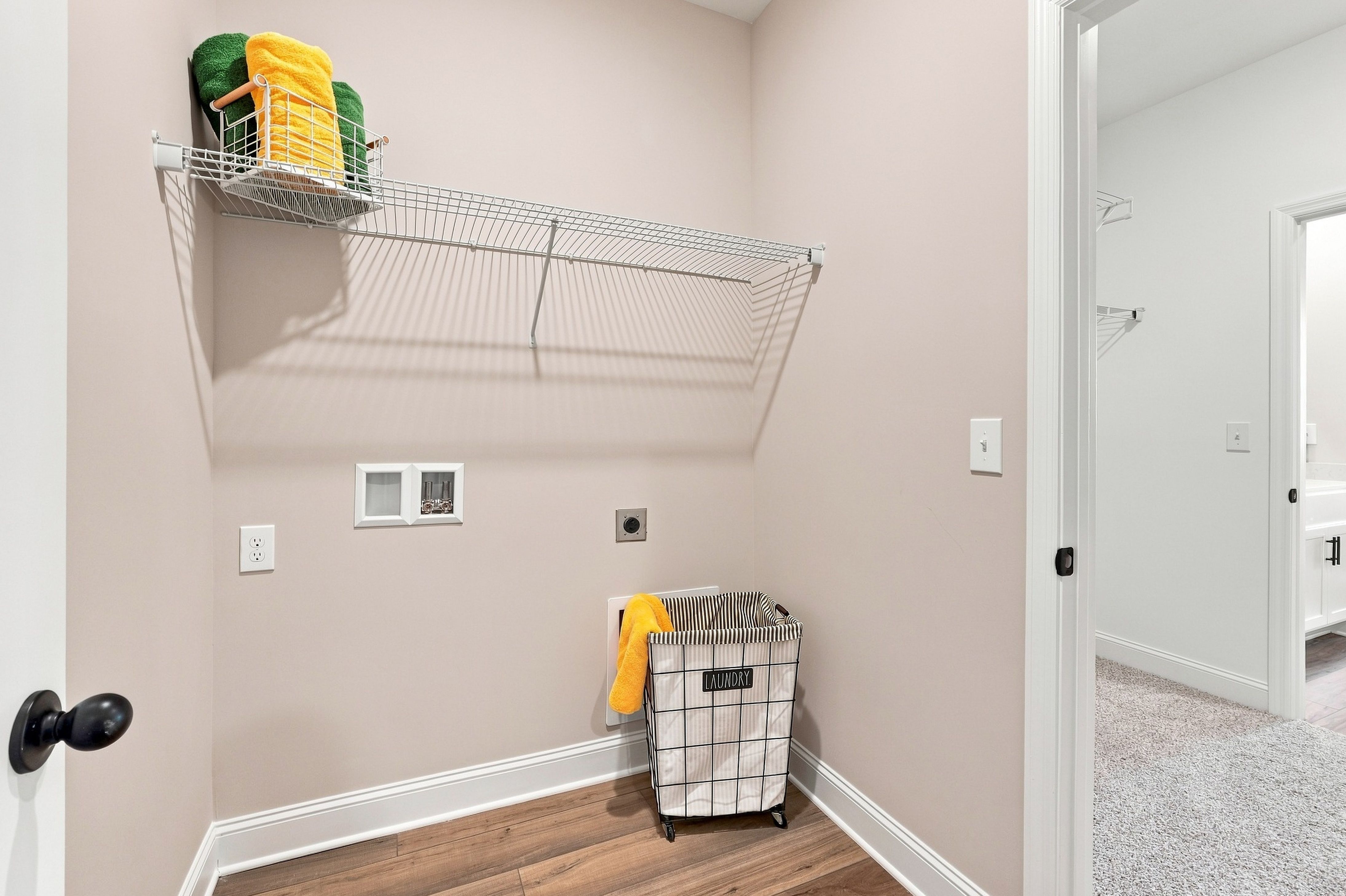 Laundry room with wire shelving and hamper at Bailey Park by Davidson Homes in Fayetteville, Tennessee, featuring wood-look flooring