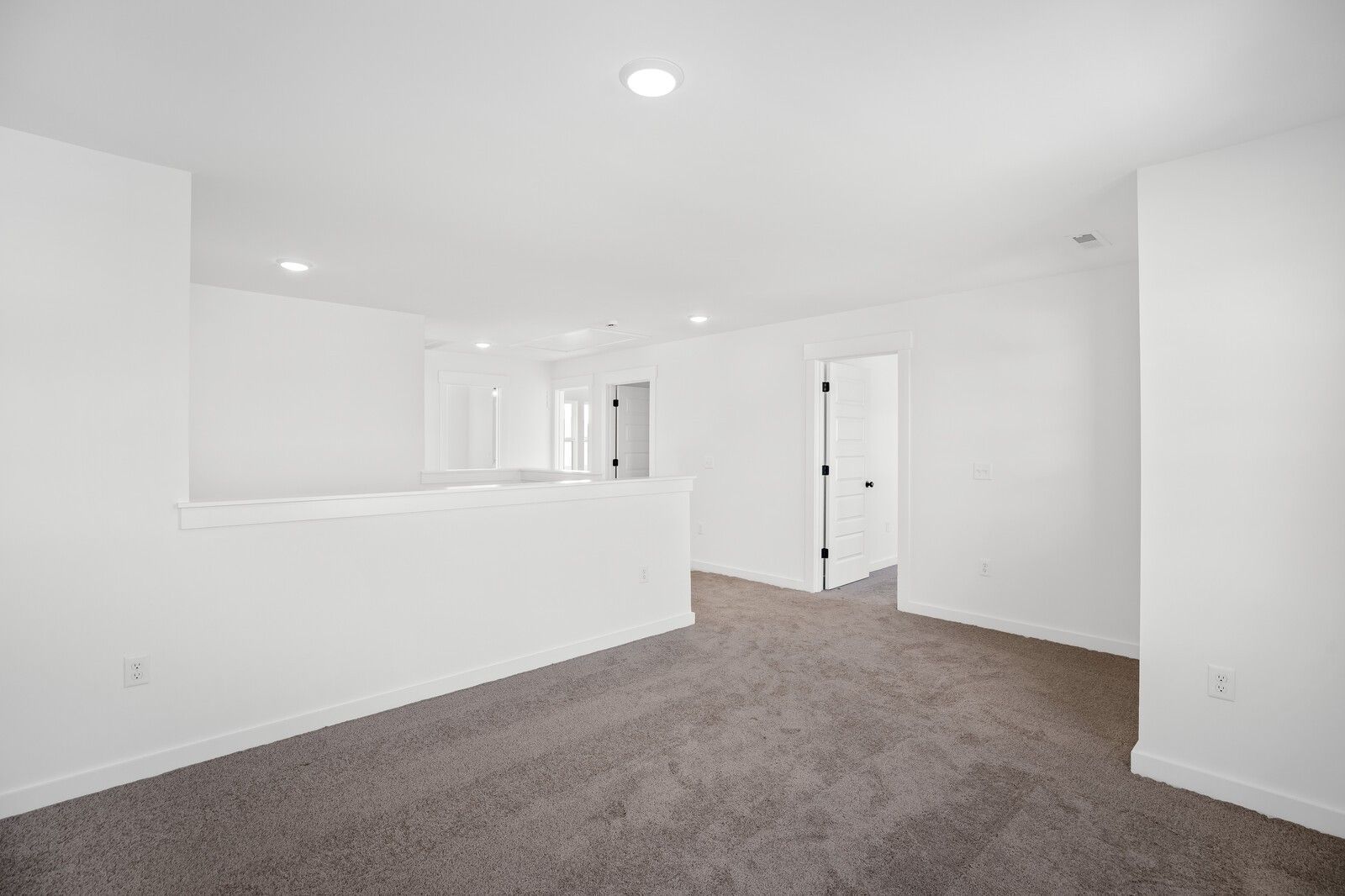 Spacious upstairs hallway with white walls, gray carpet, balcony railing, and recessed lights in Davidson Homes The Willow C, Gallatin, TN