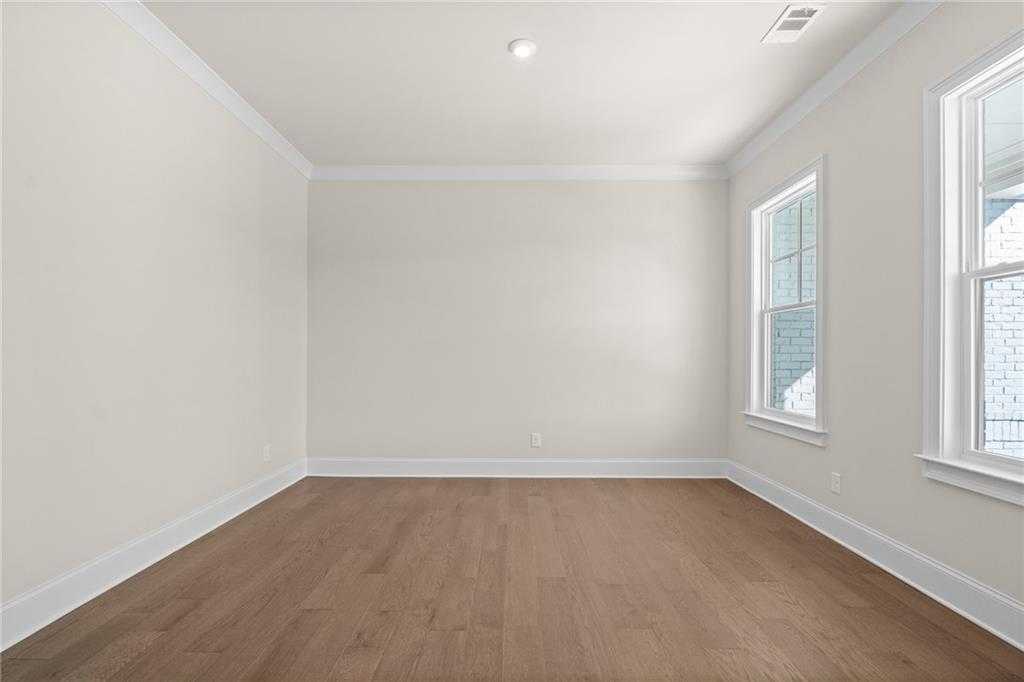 Bright empty bedroom with hardwood floors, white walls, and large windows in Davidson Homes The Arlington A, East Cobb, Georgia