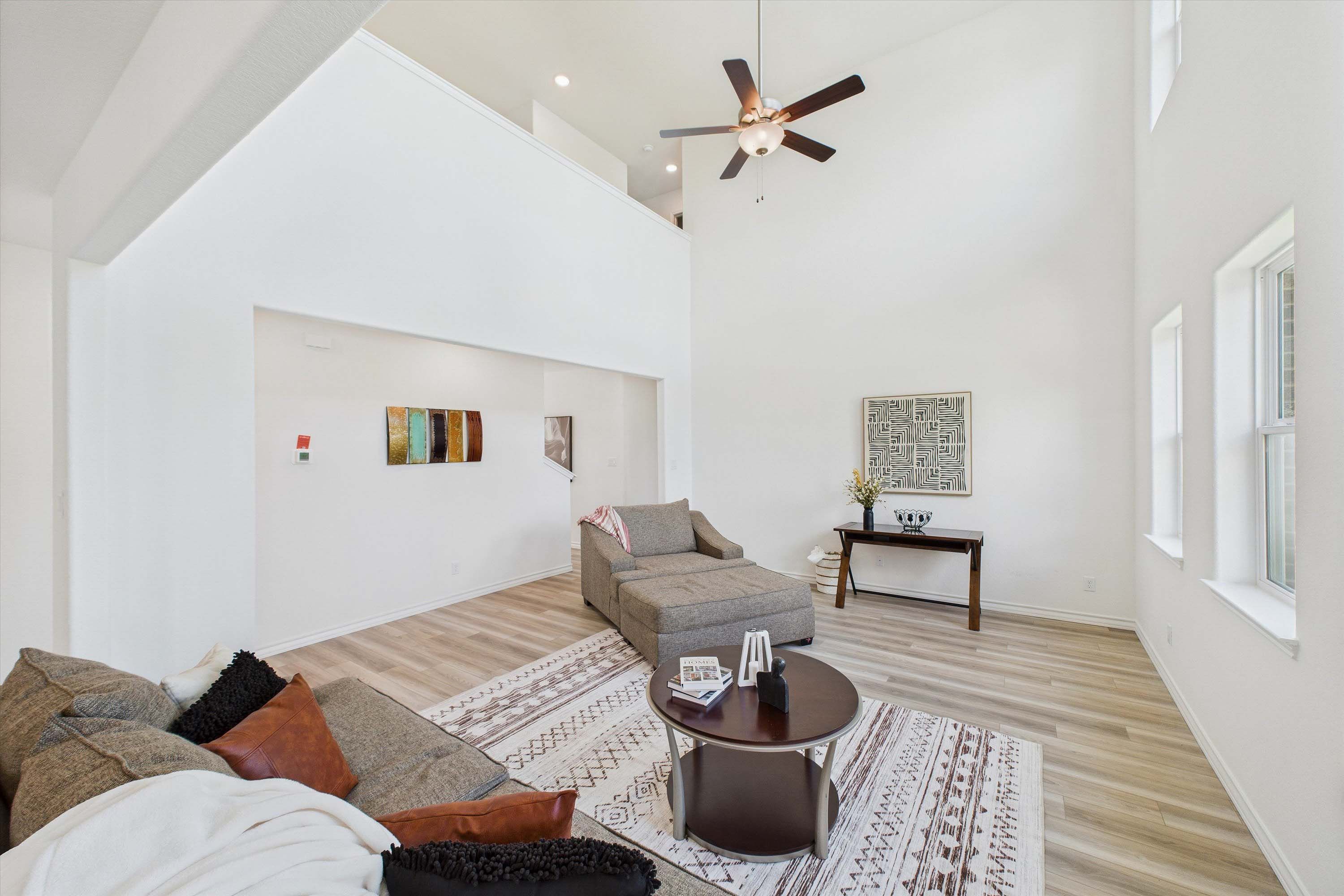 Spacious two-story living area in The Danbury featuring soaring ceilings, modern decor, and light wood-style flooring.