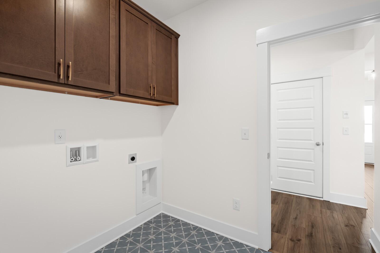 Laundry room with dark wood cabinets and patterned tile flooring in The Prairie C plan at Woods Crossing, Gallatin, TN.