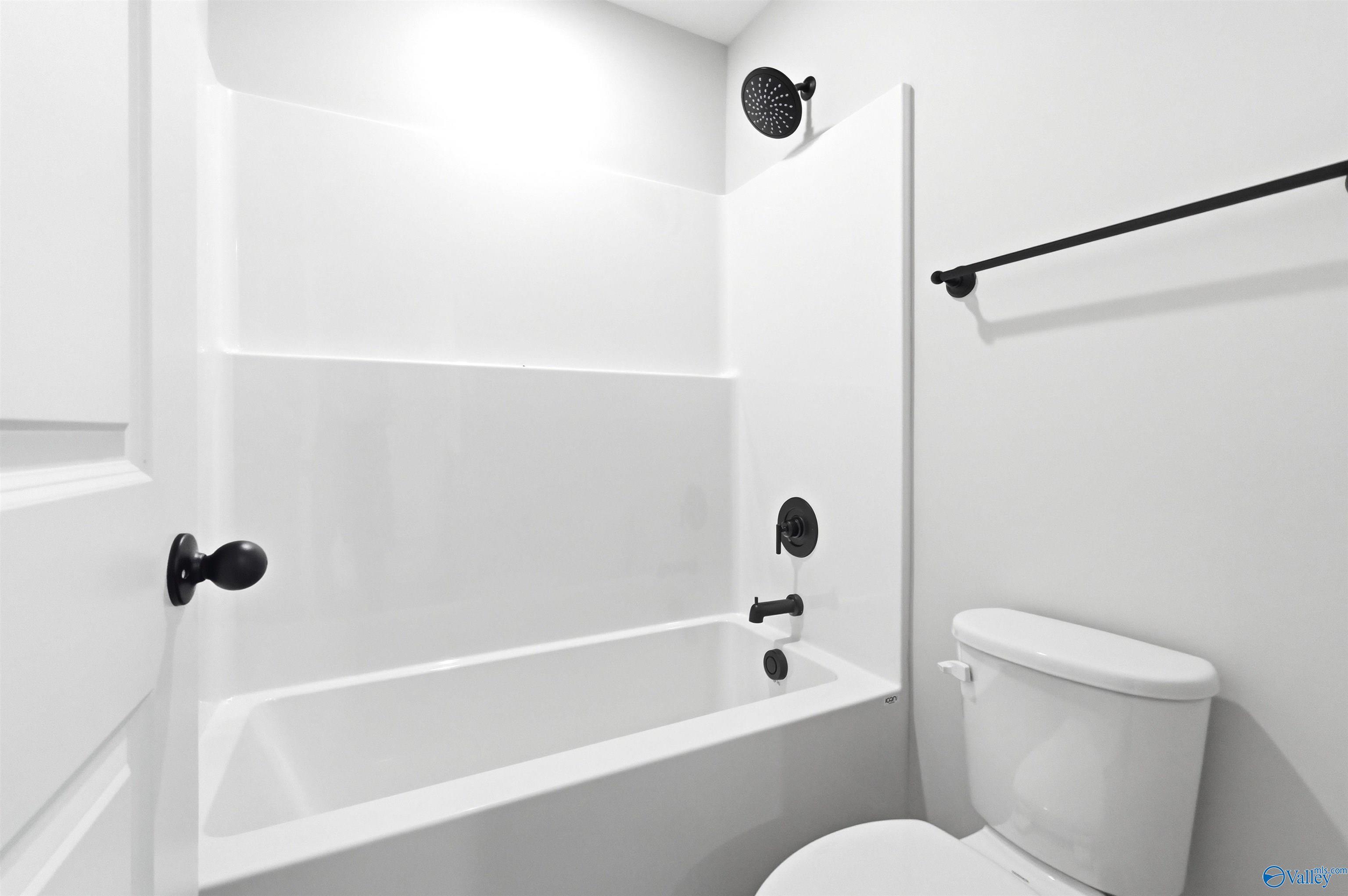 Modern bathroom with white tub-shower combo and black fixtures in The Chelsea D floor plan at Berry Cove, New Market, AL.