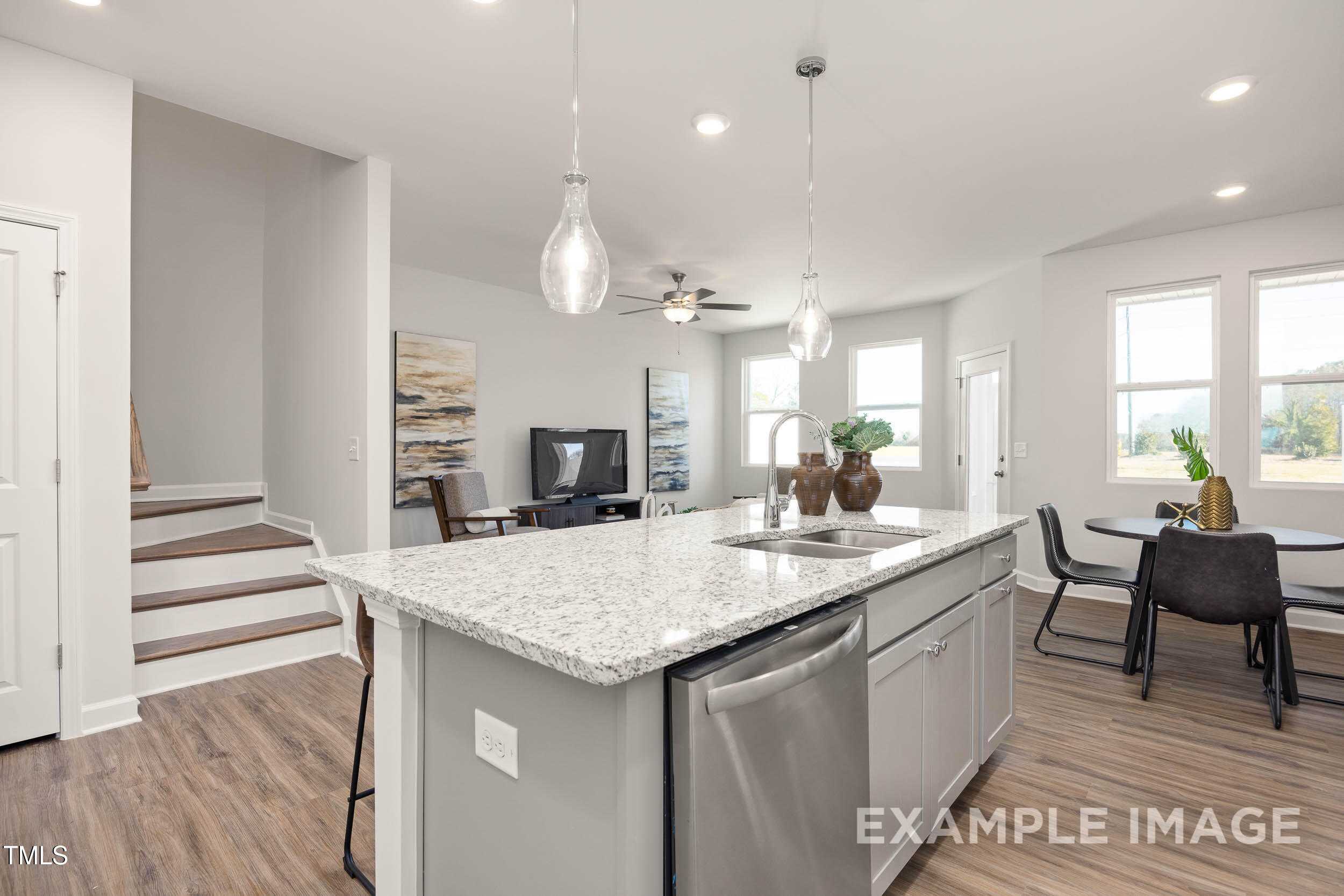 Open-concept kitchen with granite island, stainless dishwasher, pendant lights, and dining nook in 3-bedroom Davidson Homes Graham plan, Fuquay-Varina, NC