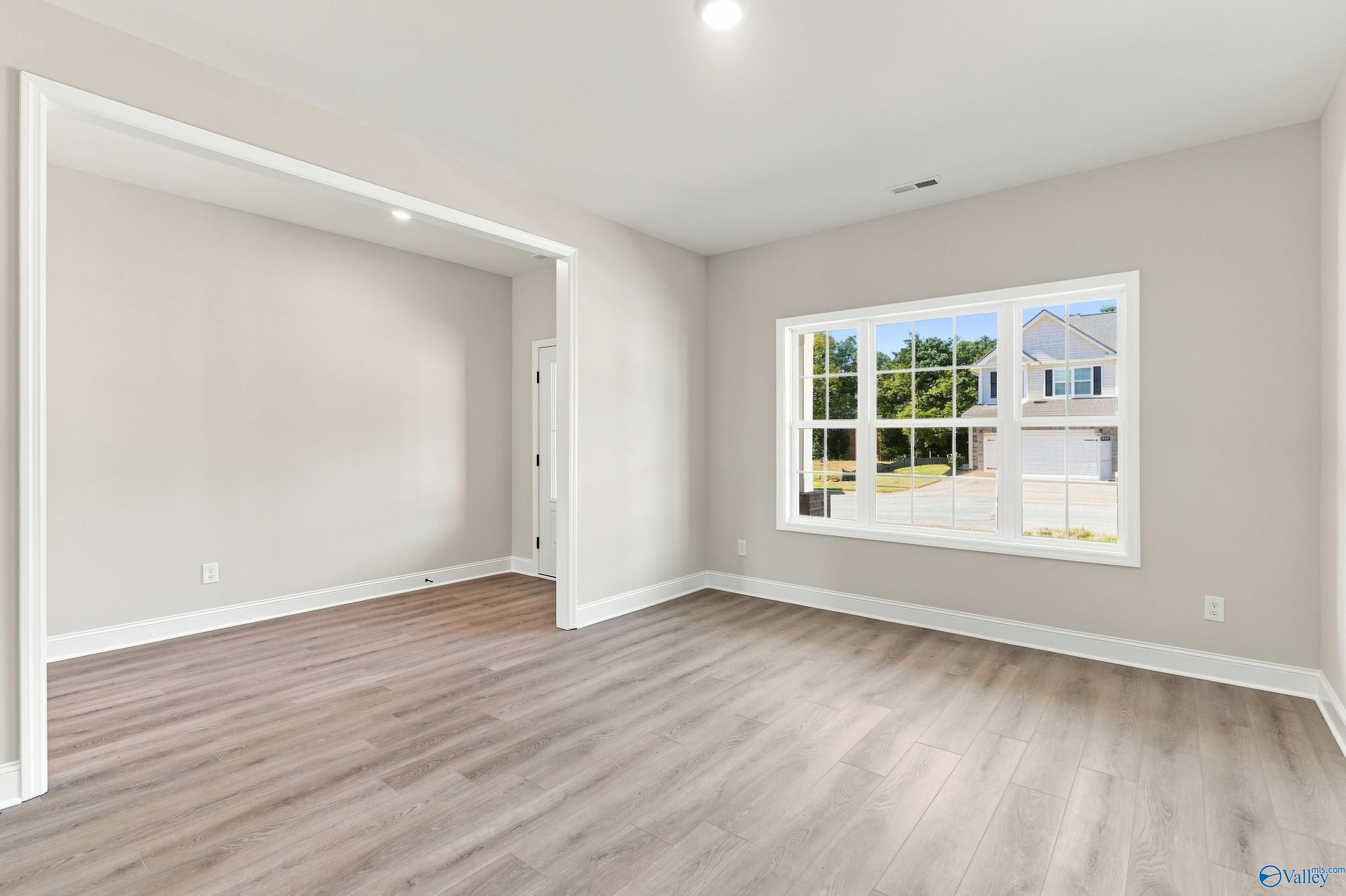Bright open-concept living room with luxury vinyl plank flooring and large front window in Davidson Homes Chelsea B, New Market, AL