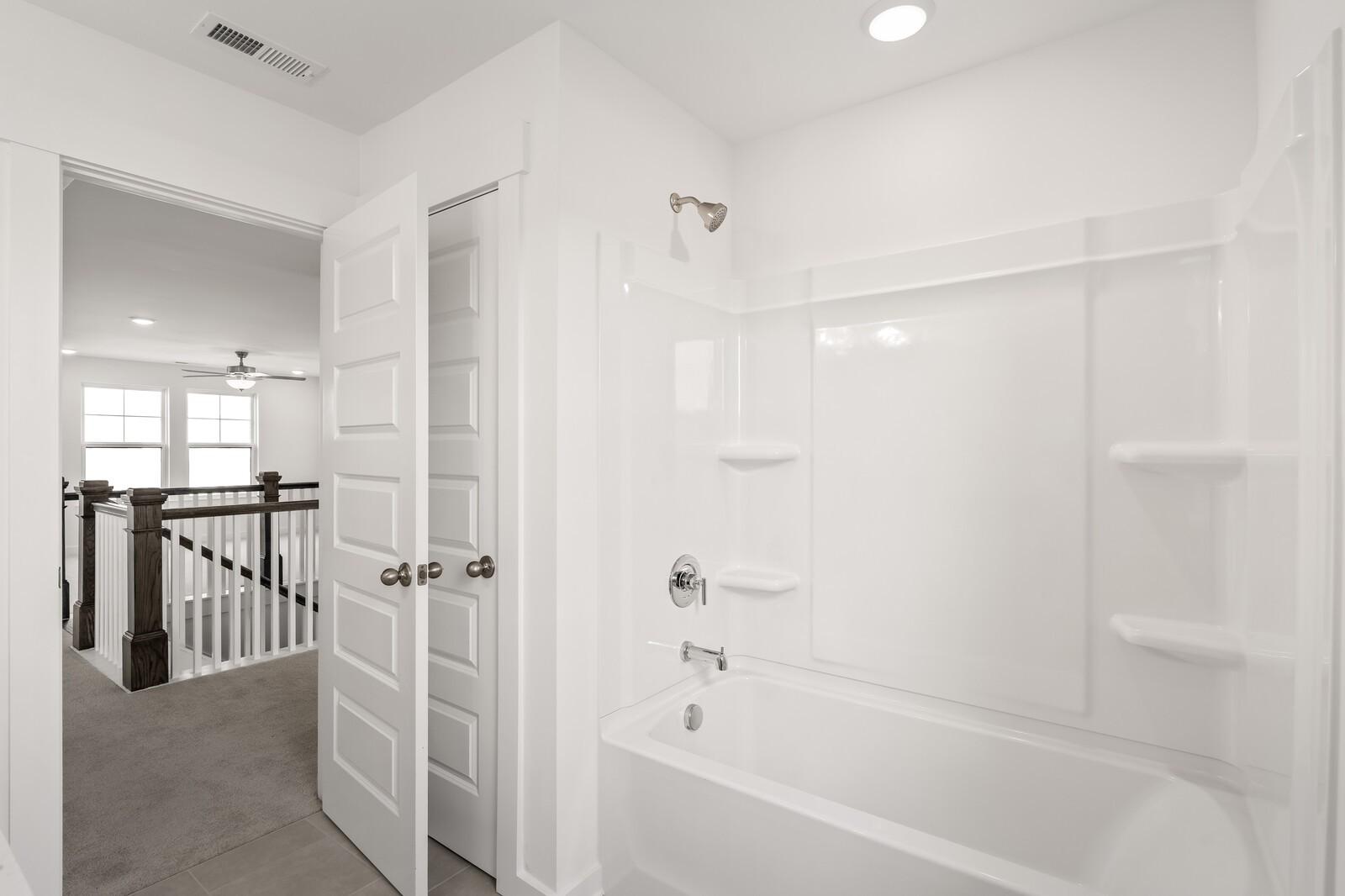 Bright white upstairs bathroom with deep soaking tub, glass shower doors, and built-in shelves in Davidson Homes The Willow D, Mt. Juliet