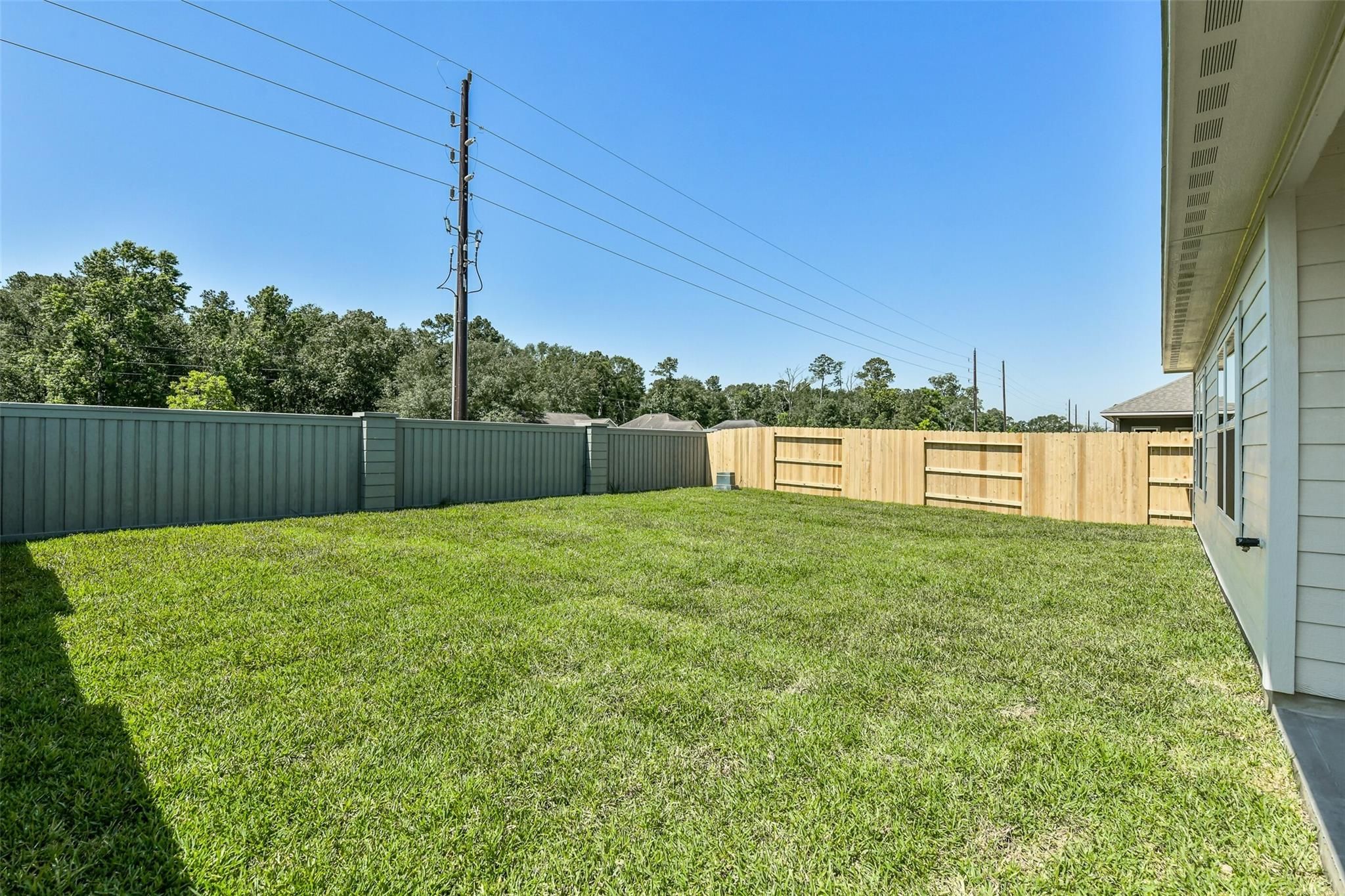 Private backyard with lush green lawn and wooden privacy fence in Davidson Homes The Daphne H, Sundance Cove, Crosby, Texas