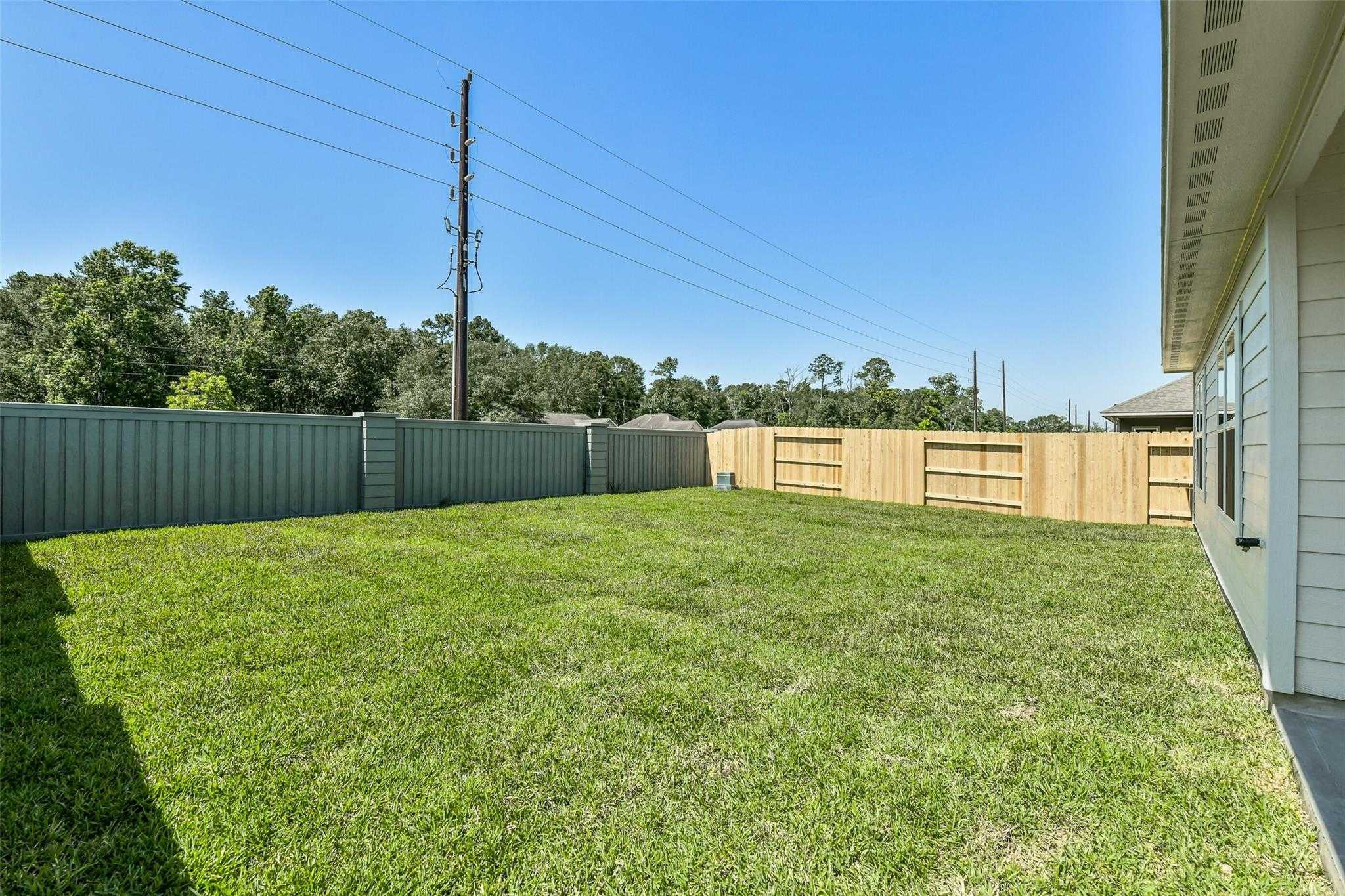 Private backyard with lush green lawn and wooden privacy fence in Davidson Homes The Daphne H, Sundance Cove, Crosby, Texas