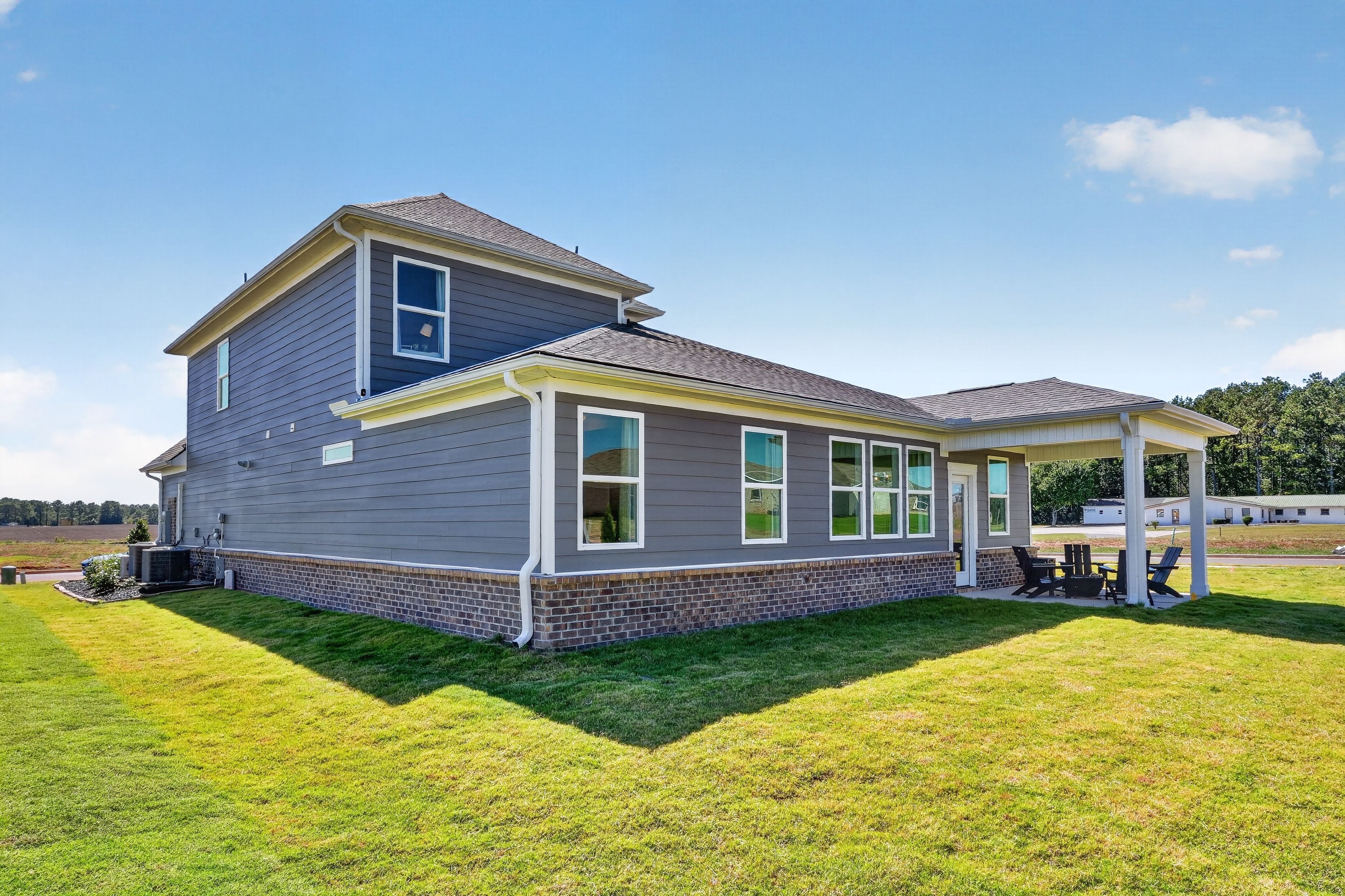 Gray two-story home exterior with brick accents and covered patio at Evergreen Mill by Davidson Homes in Madison, Alabama