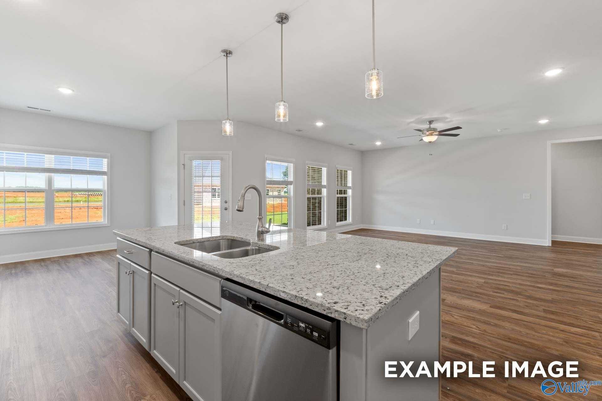 Open-concept kitchen with granite island, stainless sink, dishwasher, and French doors to backyard in Davidson Homes The Harrison B, Decatur, AL
