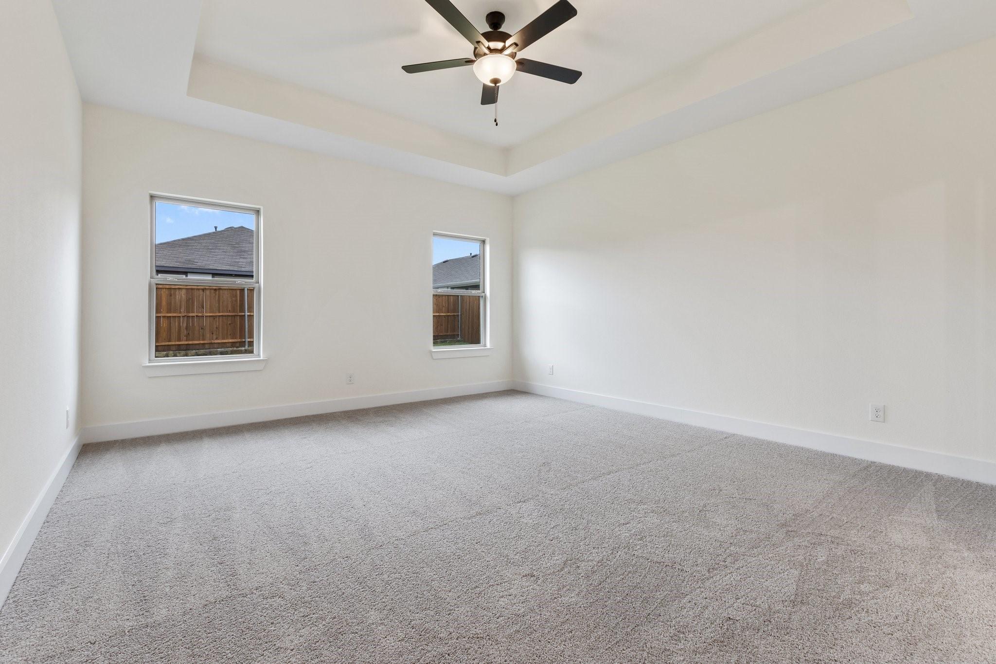 Spacious bedroom with tray ceiling and ceiling fan in The Rockford C floor plan at Waverly Estates, Josephine, Texas.