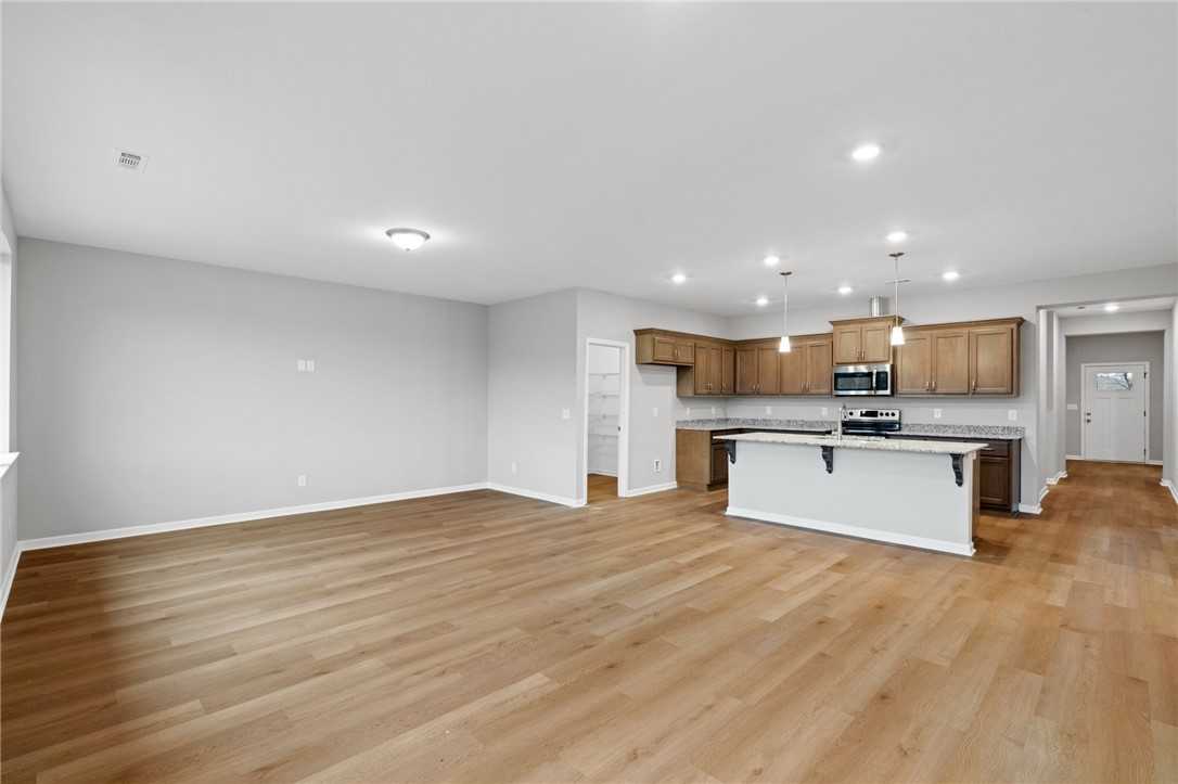 Open-concept kitchen with light wood cabinets, white island and hardwood floors in Davidson Homes The Luna B, Opelika, Alabama