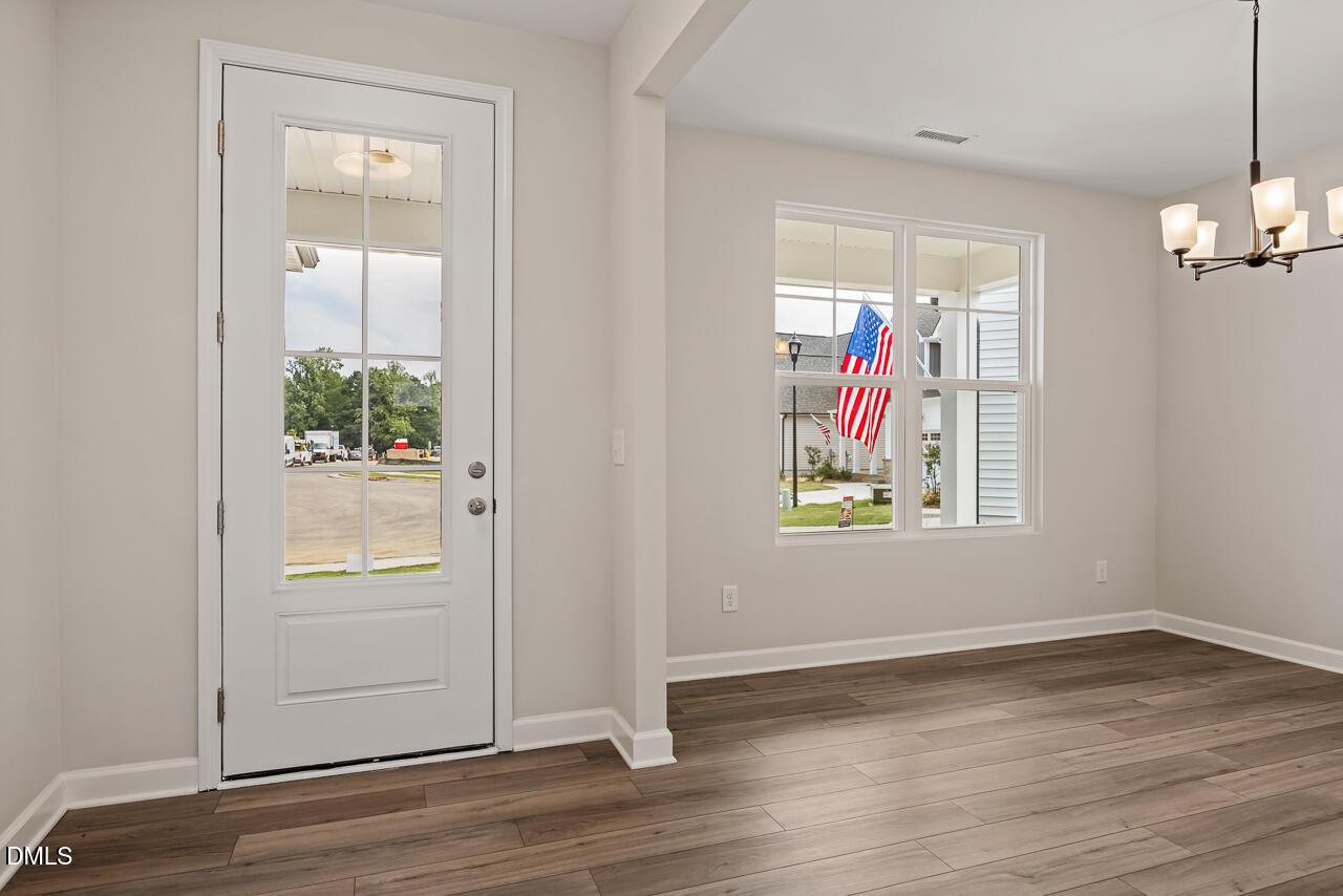 Bright dining area with modern chandelier and glass door in The Ash C floor plan at Woodland Crossing, Zebulon, NC.