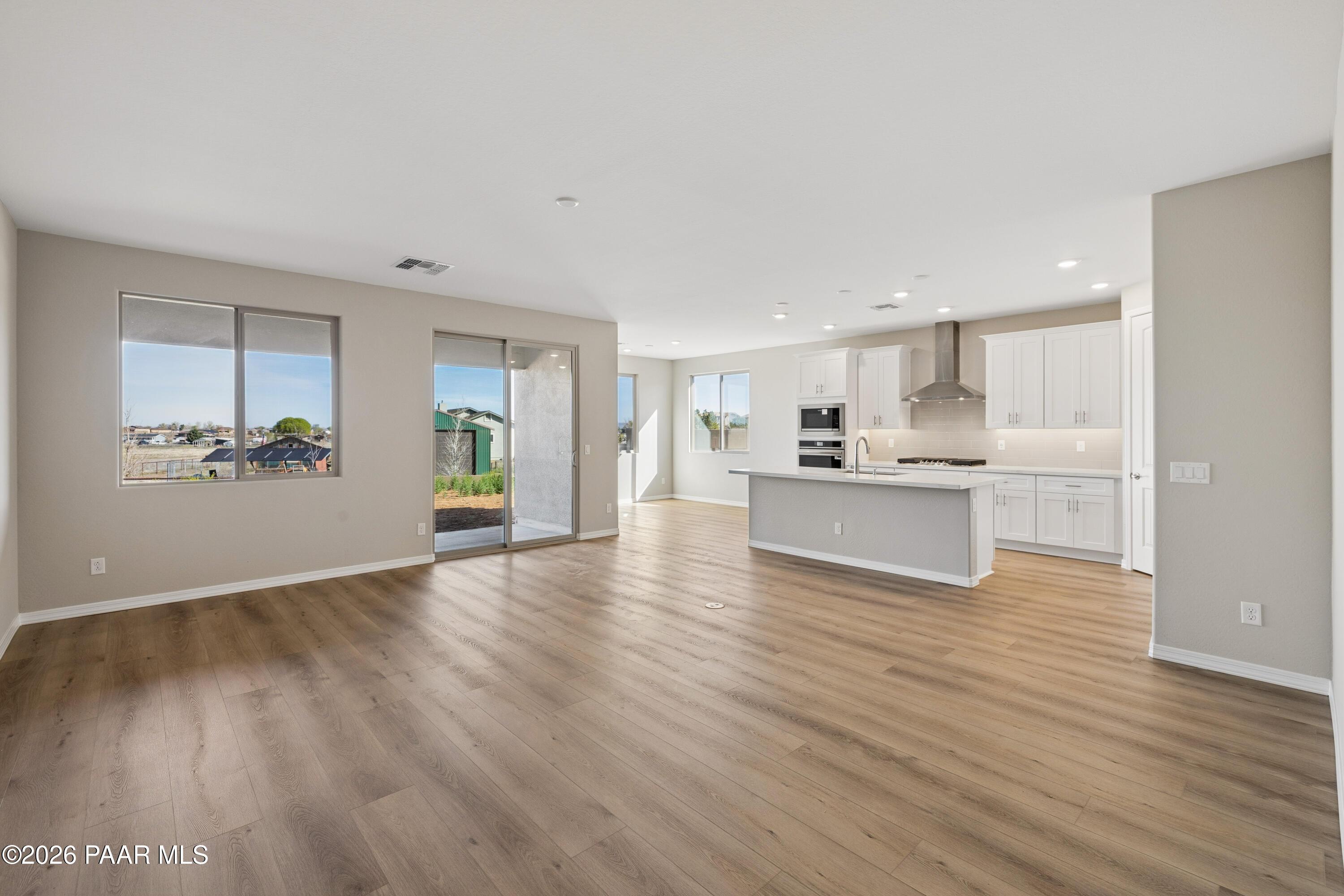 Open-concept kitchen with white cabinets, large island, stainless appliances, and sliding doors to covered patio in Davidson Homes The Harmony A, Prescott Valley, AZ