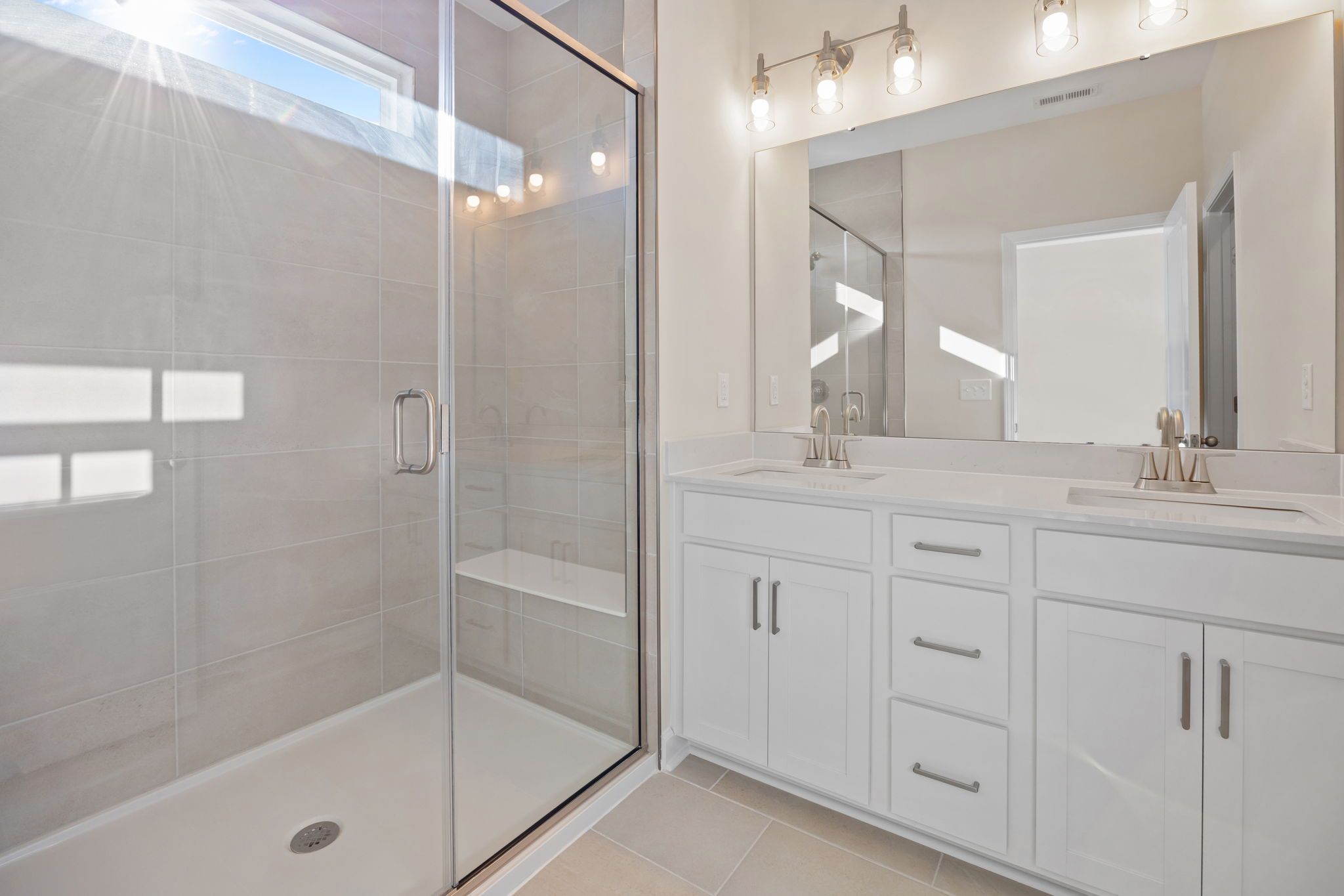 Modern bathroom with double vanity and glass-enclosed walk-in shower at Forestville Yard in Knightdale, NC by Davidson Homes
