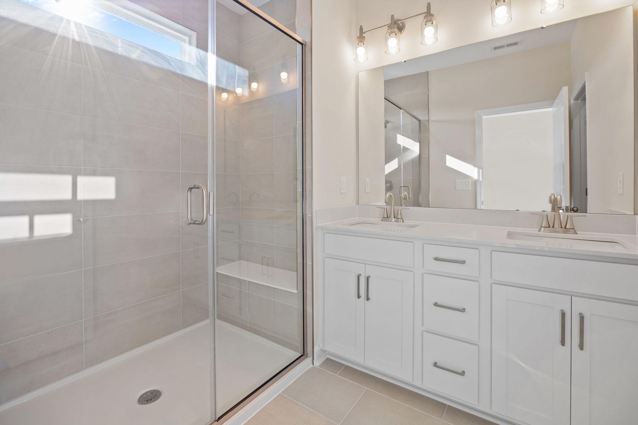 Modern bathroom with double vanity and glass-enclosed walk-in shower at Forestville Yard in Knightdale, NC by Davidson Homes