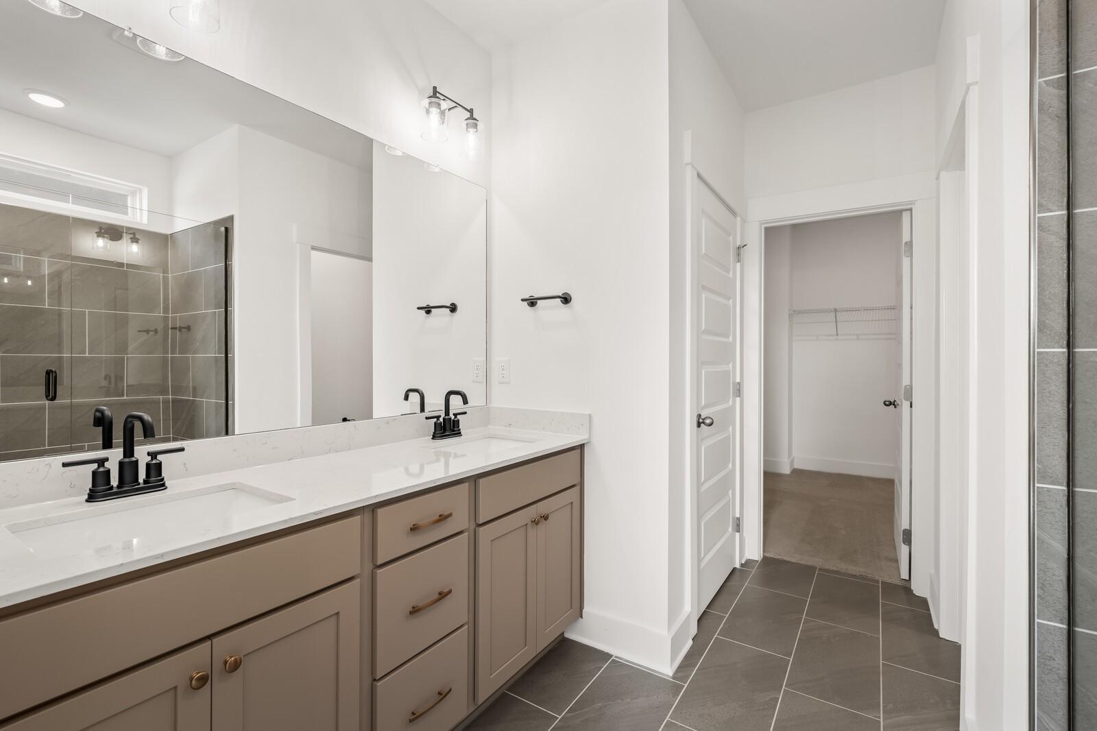 Modern master bathroom with double beige vanity, quartz counters, dual sinks, and glass walk-in shower in Davidson Homes The Ash A, Gallatin, TN